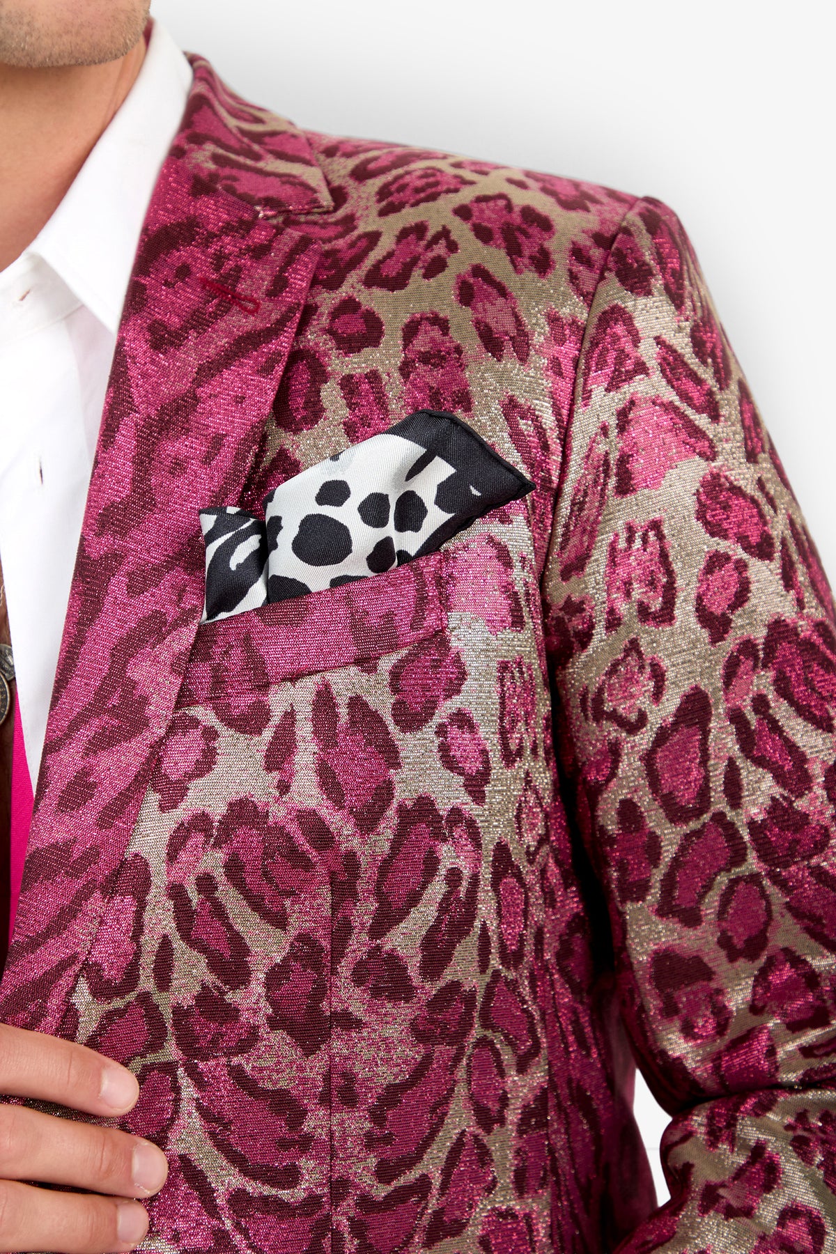 A person wearing the Thurston Blazer—a metallic pink and gold leopard print jacket—paired with a white shirt and a black-and-white animal print pocket square. Only the upper torso is visible.