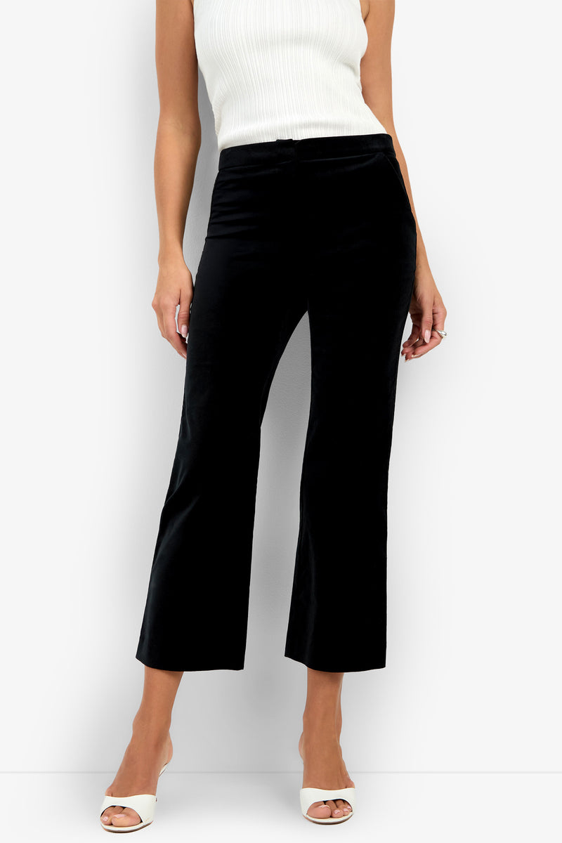 A woman is wearing the Westport Crop in black, paired with a white sleeveless ribbed top and white open-toe heels, standing against a plain background.