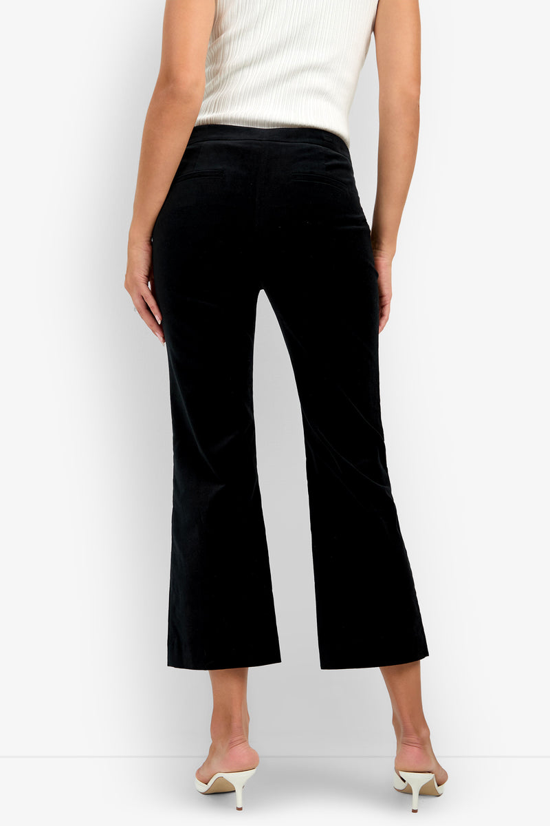 A person wearing the Westport Crop black velvet pants, a white sleeveless ribbed top, and white heeled sandals stands with their back facing the camera.