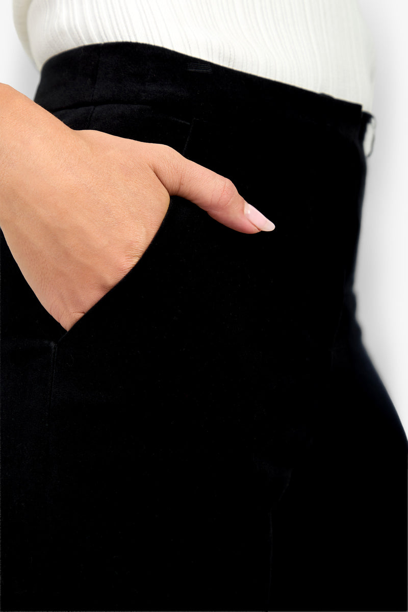 A close-up of a person wearing the Westport Crop black pants and a white ribbed top, with their left hand placed in the front pocket of the pants.