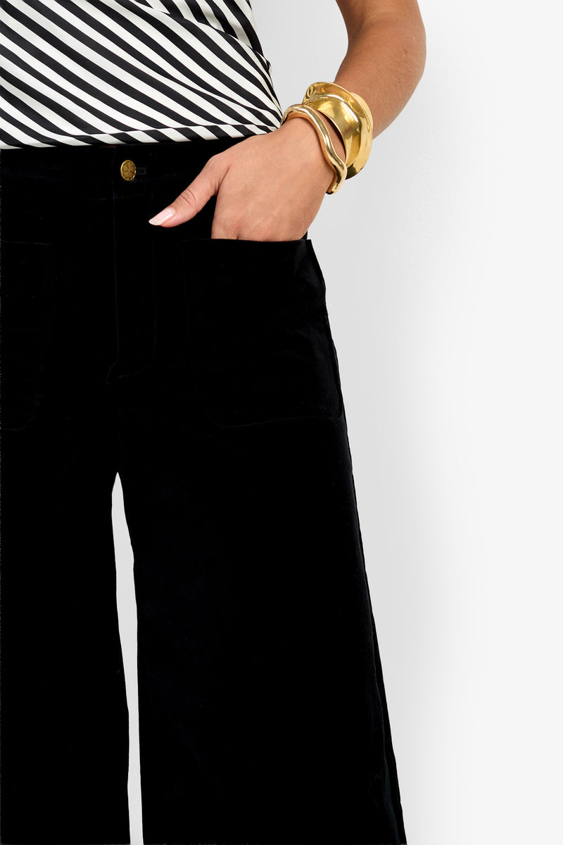 A person wearing the Talamone Pant, paired with a black-and-white striped top and gold bangles, rests their right hand in their pocket against a white background.
