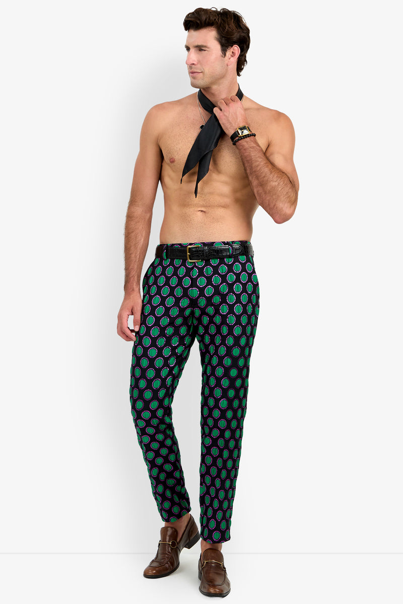 A shirtless man poses against a plain white background, wearing the Clyde Slim Trouser styled with brown shoes and holding a black necktie while looking to the side.