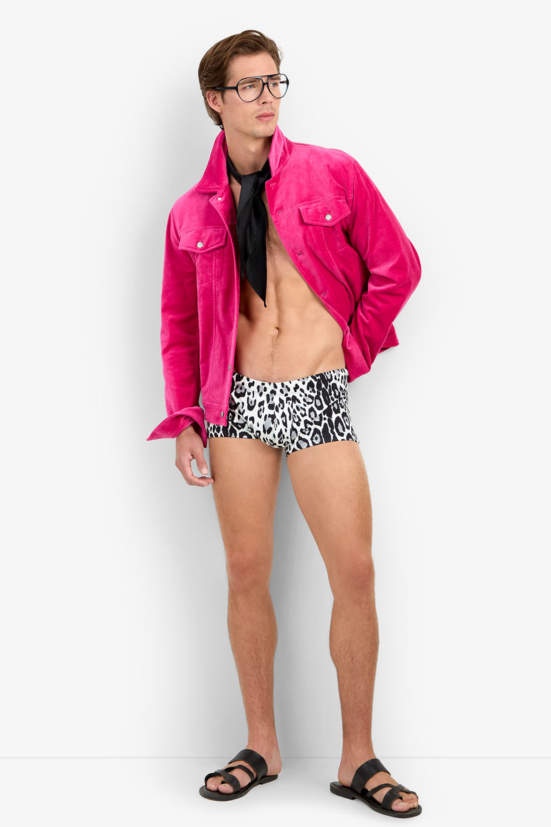 A man wearing glasses, a bright pink jacket, a black neck scarf, MONTEGO BAY SWIM TRUNK, and black sandals stands against a plain white background.