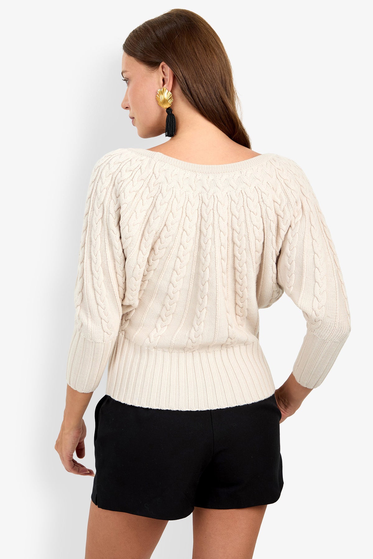 A person seen from behind wears a TYSON off-white, 100% wool cable-knit sweater with three-quarter sleeves and black shorts.
