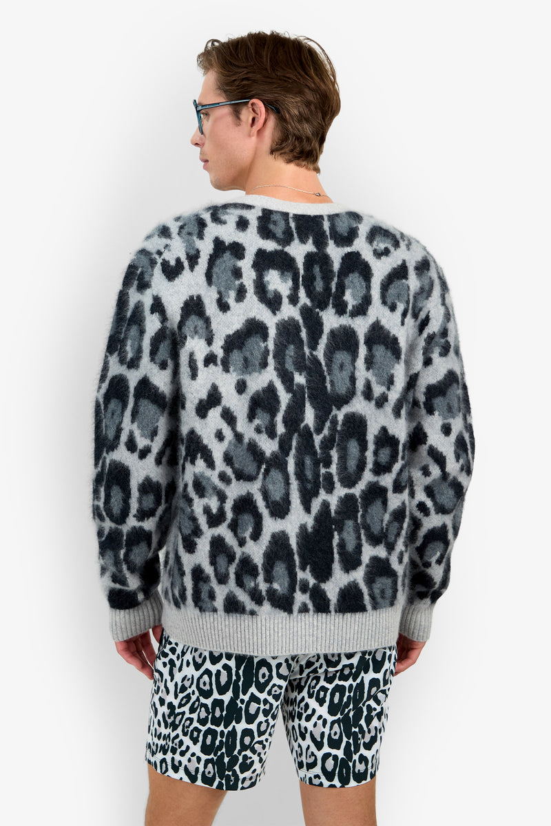 Wearing the LEO FUZZY CARDIGAN, a person faces away from the camera, pairing it with black-and-white leopard print shorts while standing against a plain white background.