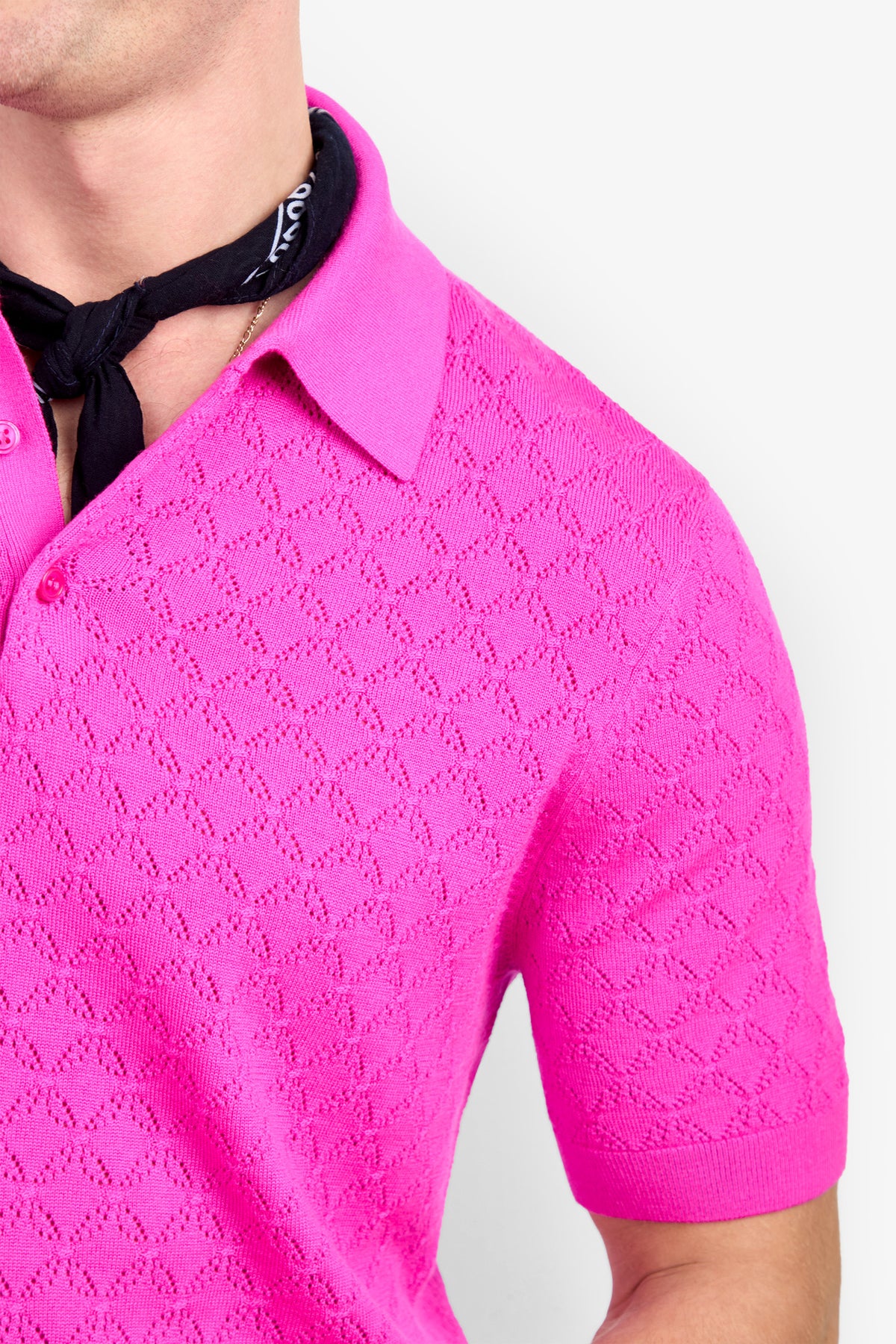 Bright pink Waylen Polo with short sleeves, a textured knit pattern, and a black neckerchief.