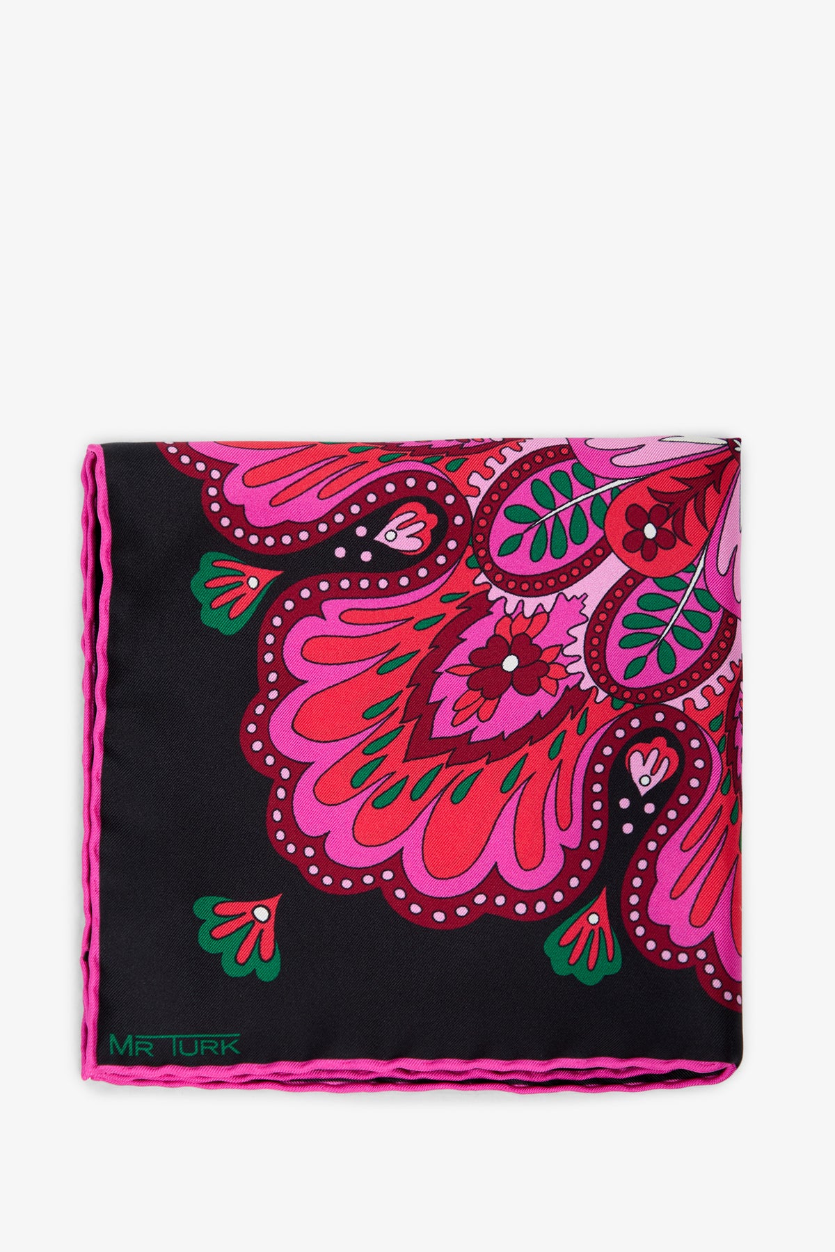 The Sautoir Silk Pocket Square is a folded black pocket square adorned with pink, red, and green paisley patterns and finished with pink edging. “MR TURK” is printed in green text on the lower left corner.