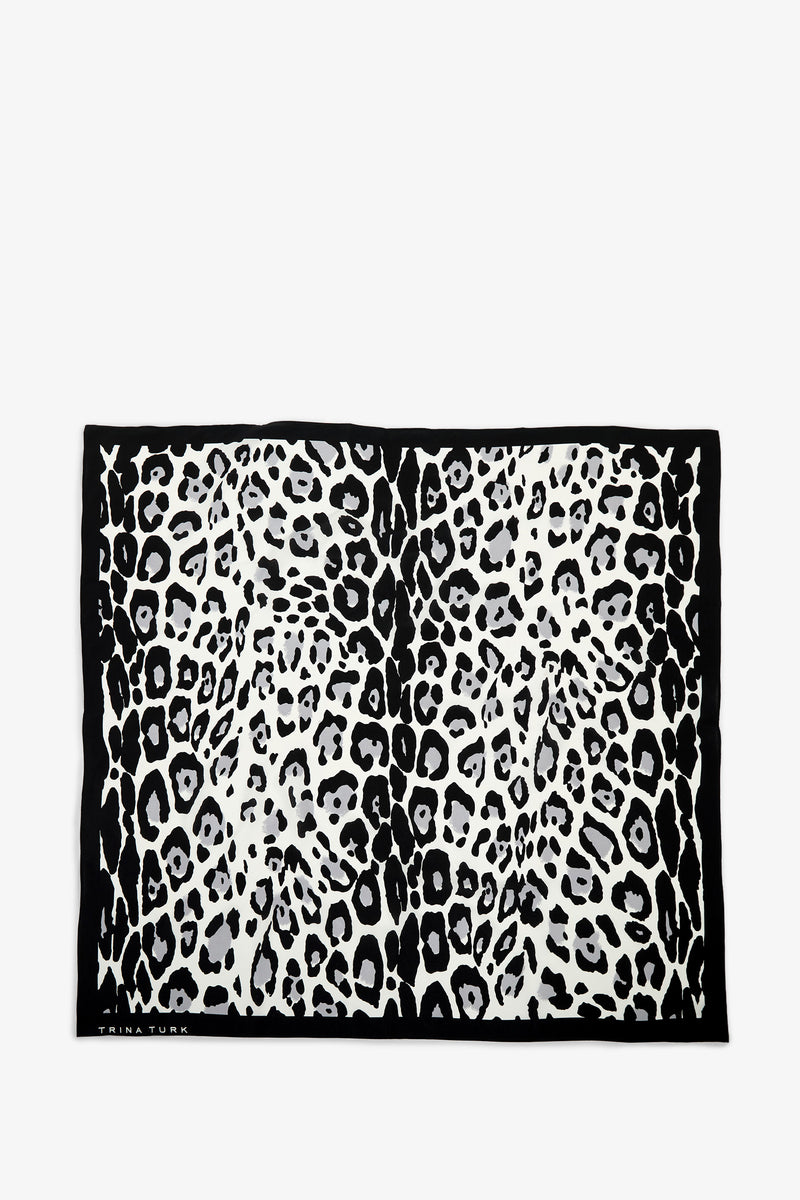 The Snow Leopard Silk Scarf is a rectangular accessory featuring a black and white leopard print pattern framed by a solid black border.