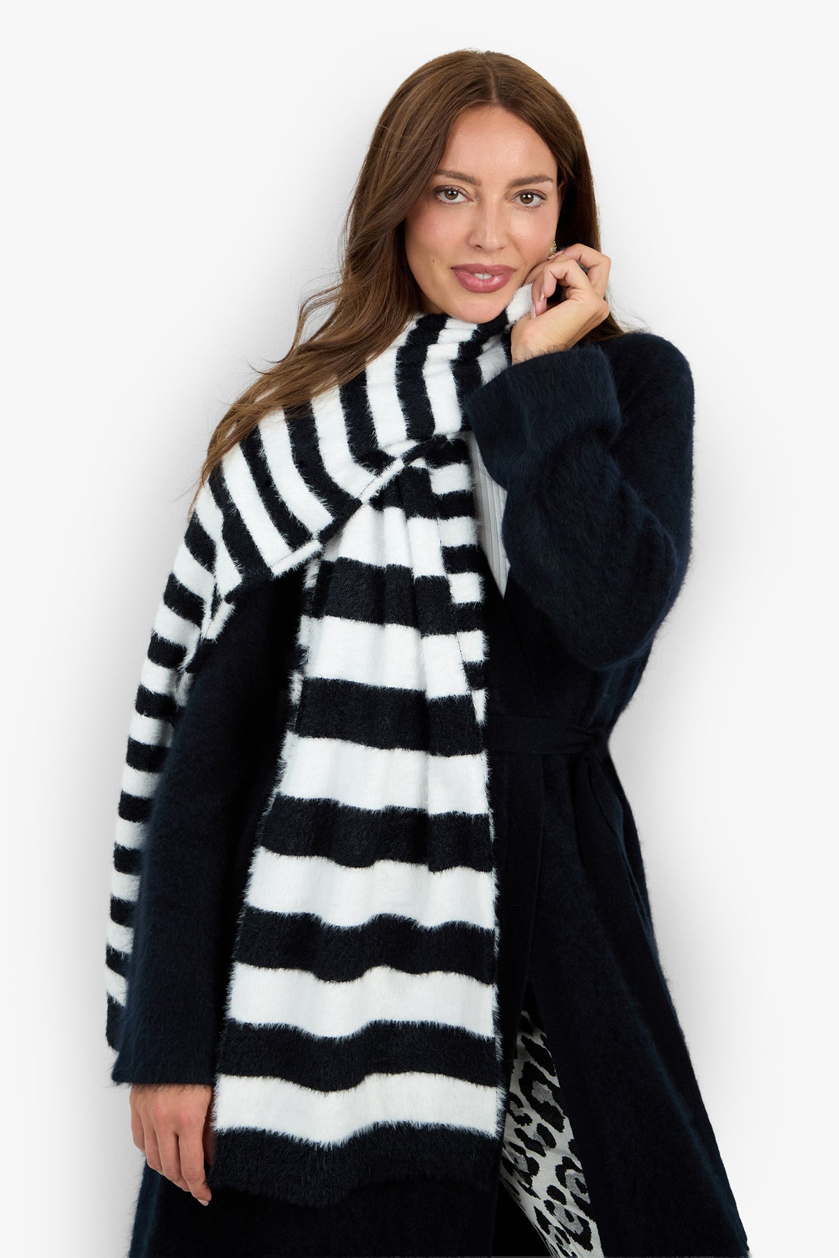 A woman wears a long, fluffy RAJA SCARF with broad black and white horizontal stripes draped over a dark coat.