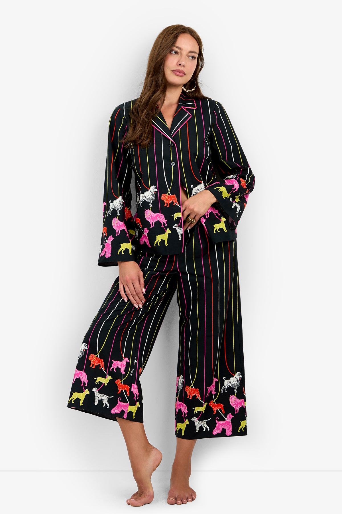 A person wearing a RUBEE PANT set in black with colorful vertical stripes and a pattern of various dog breeds on leashes.