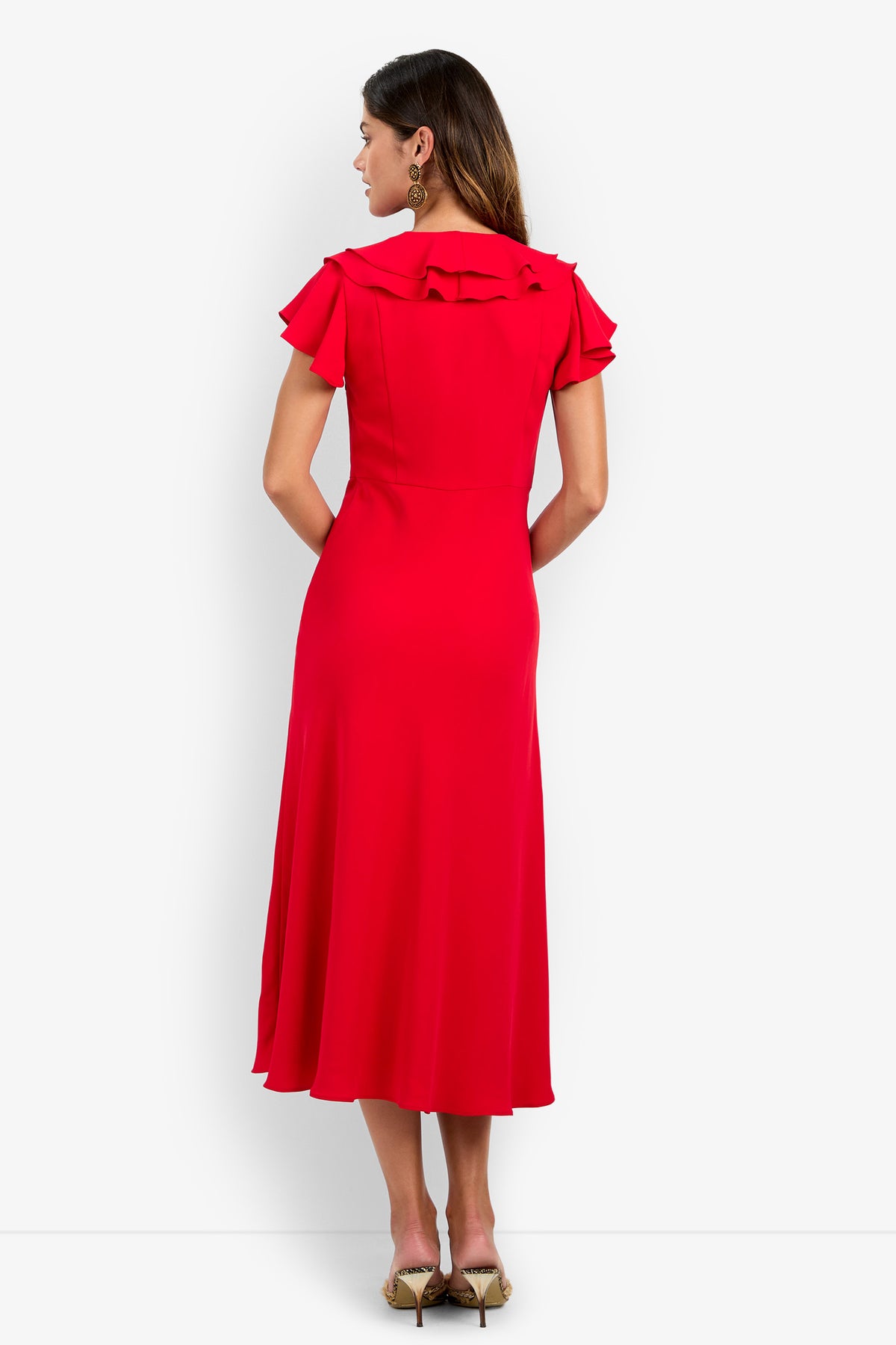 View from behind of a person wearing the PATRONS DRESS, a midi-length red polyester dress with short ruffled sleeves and a ruffled collar.