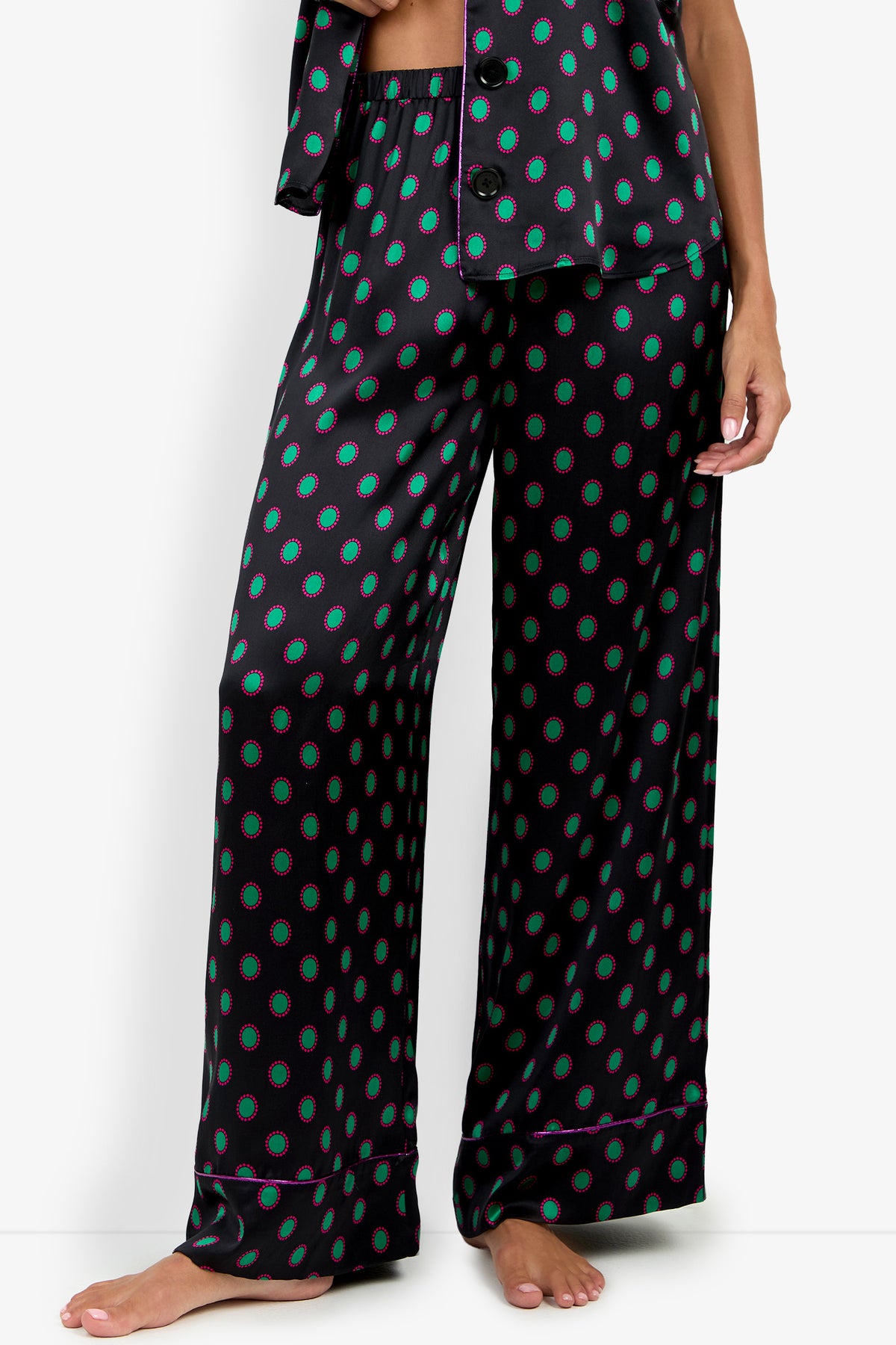 LIARA PANT black wide-leg pajama pants in 100% silk, featuring a repeating pattern of teal circles with magenta outlines and a matching pajama top visible at the waist.