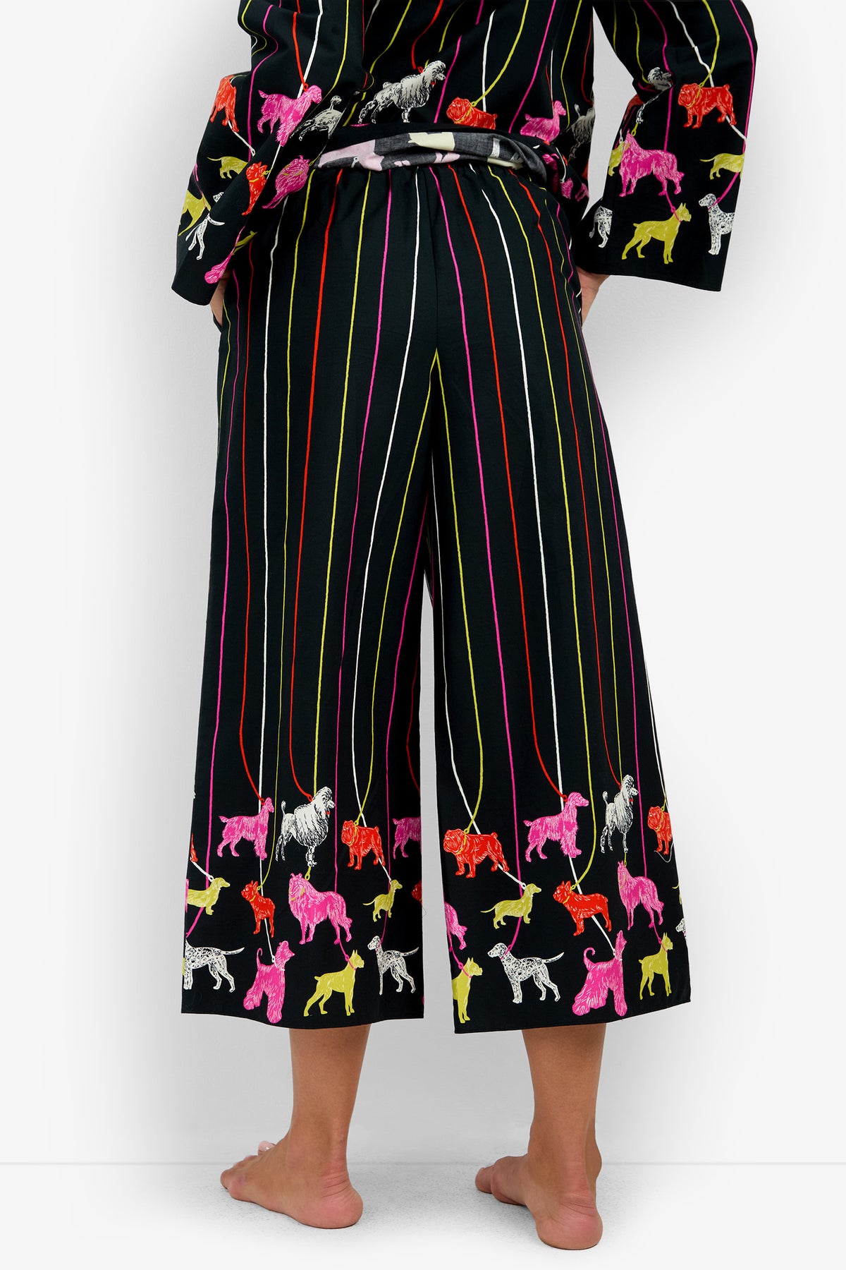RUBEE PANT black 100% cotton cropped trousers featuring vertical multi-colored stripes and a print of colorful dogs along the hem.