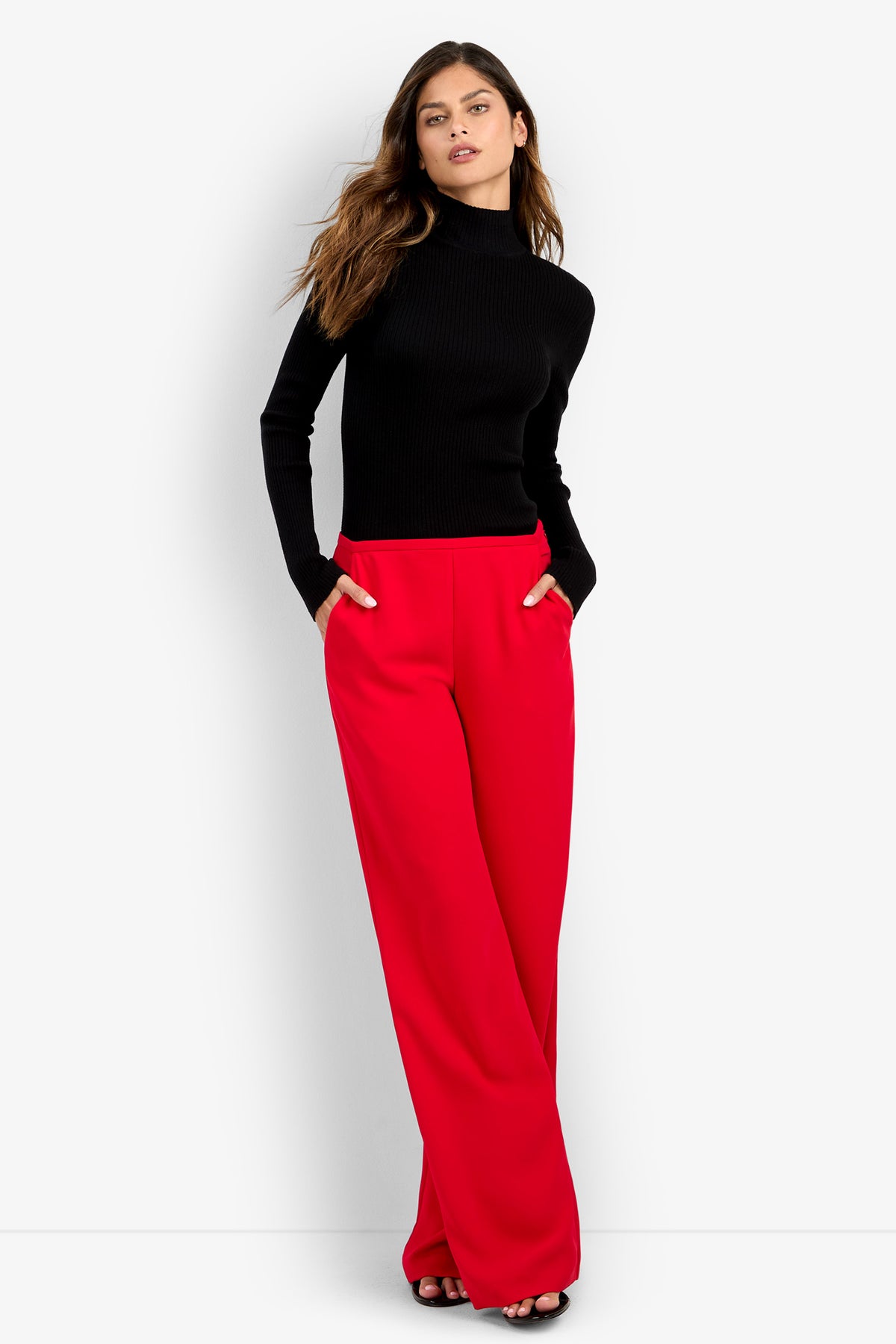 A person wearing a black long-sleeved turtleneck tucked into high-waisted red polyester TAVIA PANT wide-leg trousers.