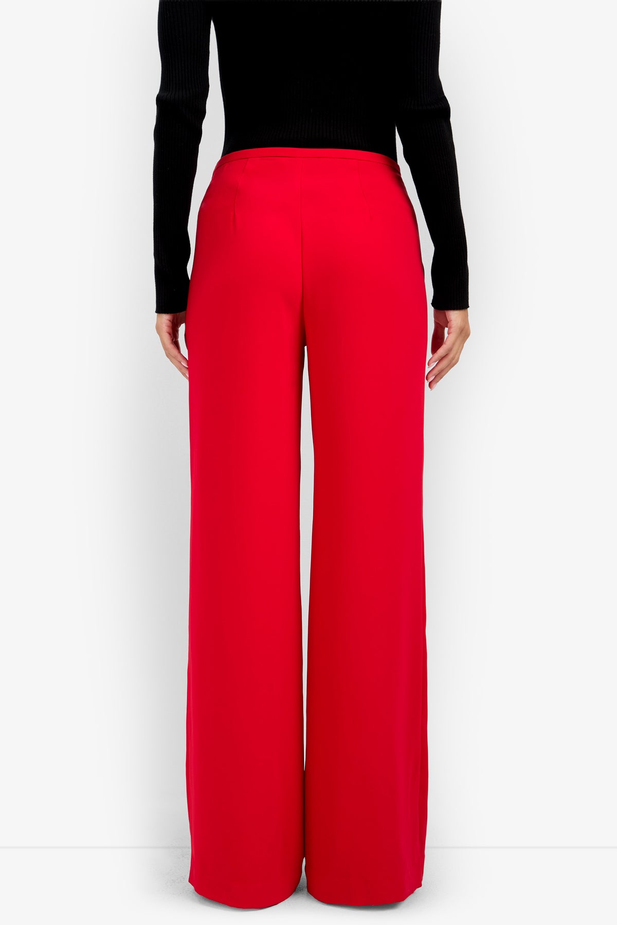Back view of a person wearing TAVIA PANT 100% polyester high-waisted red wide-leg trousers and a black long-sleeved top.