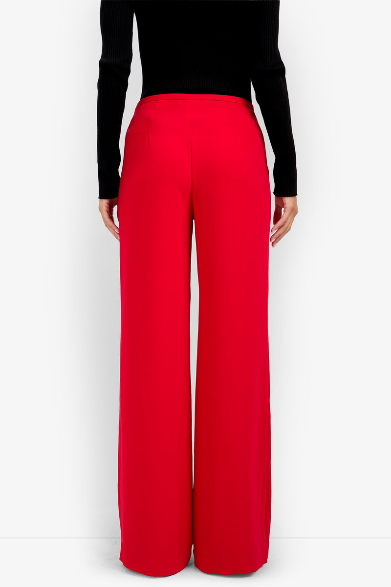 Back view of a person wearing TAVIA PANT 100% polyester high-waisted red wide-leg trousers and a black long-sleeved top.