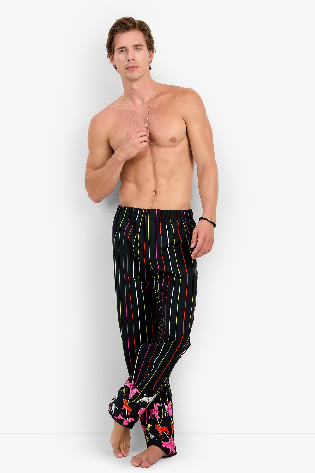 Shirtless man wearing black PJ PANT 100% cotton pajama pants featuring vertical neon stripes and a colorful animal print pattern at the cuffs.