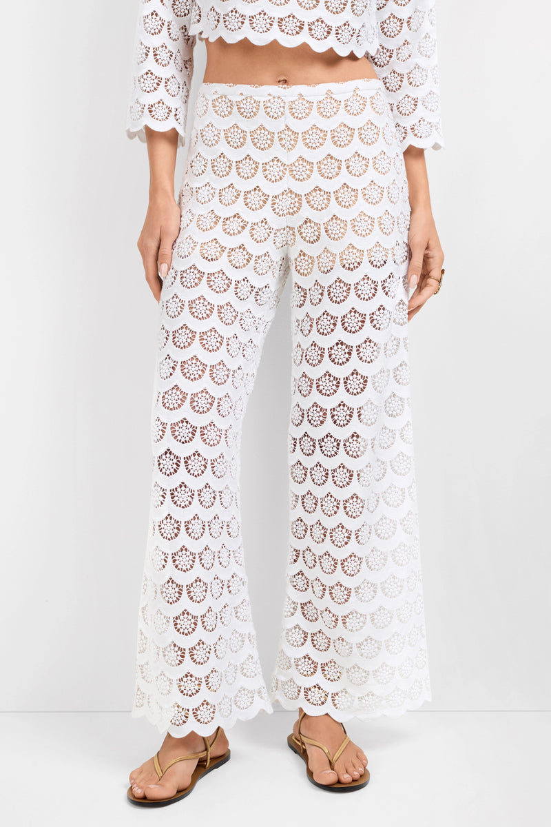 A person is wearing Dzo Dzo Crochet Lace Pants with a matching white cropped top. The high-waisted outfit features an intricate lace openwork pattern and is styled with tan sandals.
