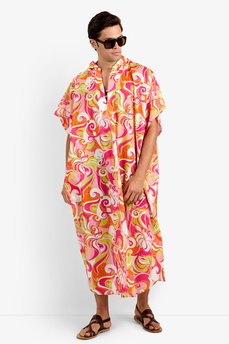 Wearing sunglasses and sandals, a person models the HURLEY CAFTAN in MULTI—a colorful, loose-fitting, hooded style crafted from soft 100% cotton with a vibrant swirl pattern—standing against a plain background.