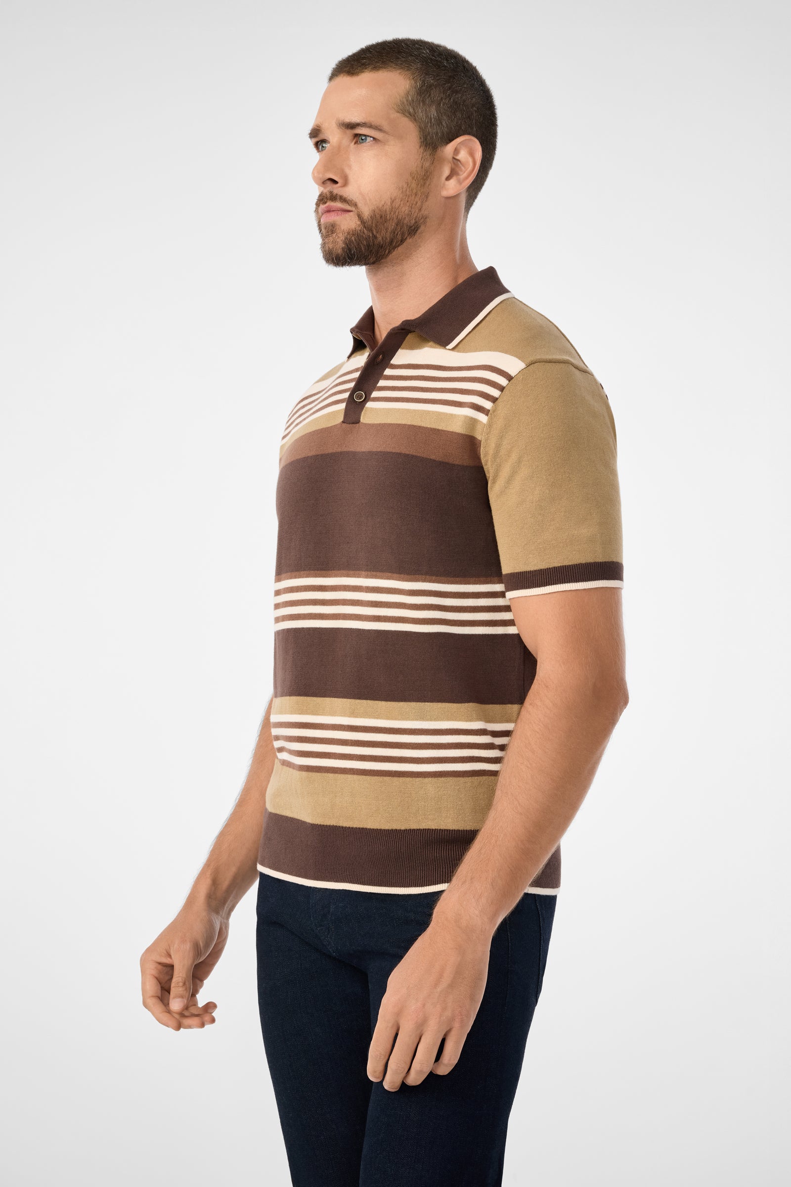 A man with short hair and a beard wears the Edward Short-Sleeve Polo in brown, beige, and cream stripes with dark pants, standing against a plain light background.