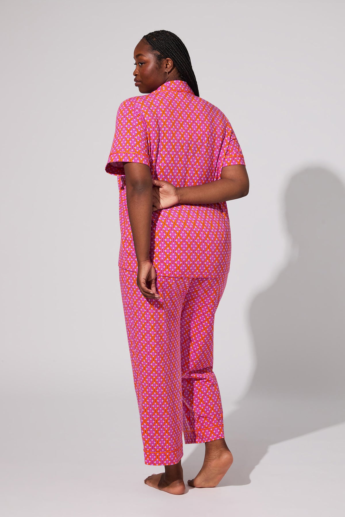 A person stands barefoot facing away, wearing the Crop Classic PJ Set - Chain Geo. One hand is behind their back and the background is plain and light-colored.