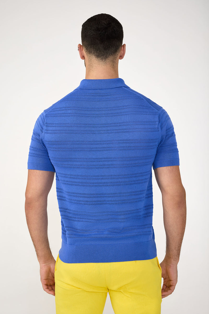 A man faces away from the camera, wearing the Edison Short-Sleeve Striped Polo and bright yellow pants against a plain light background.