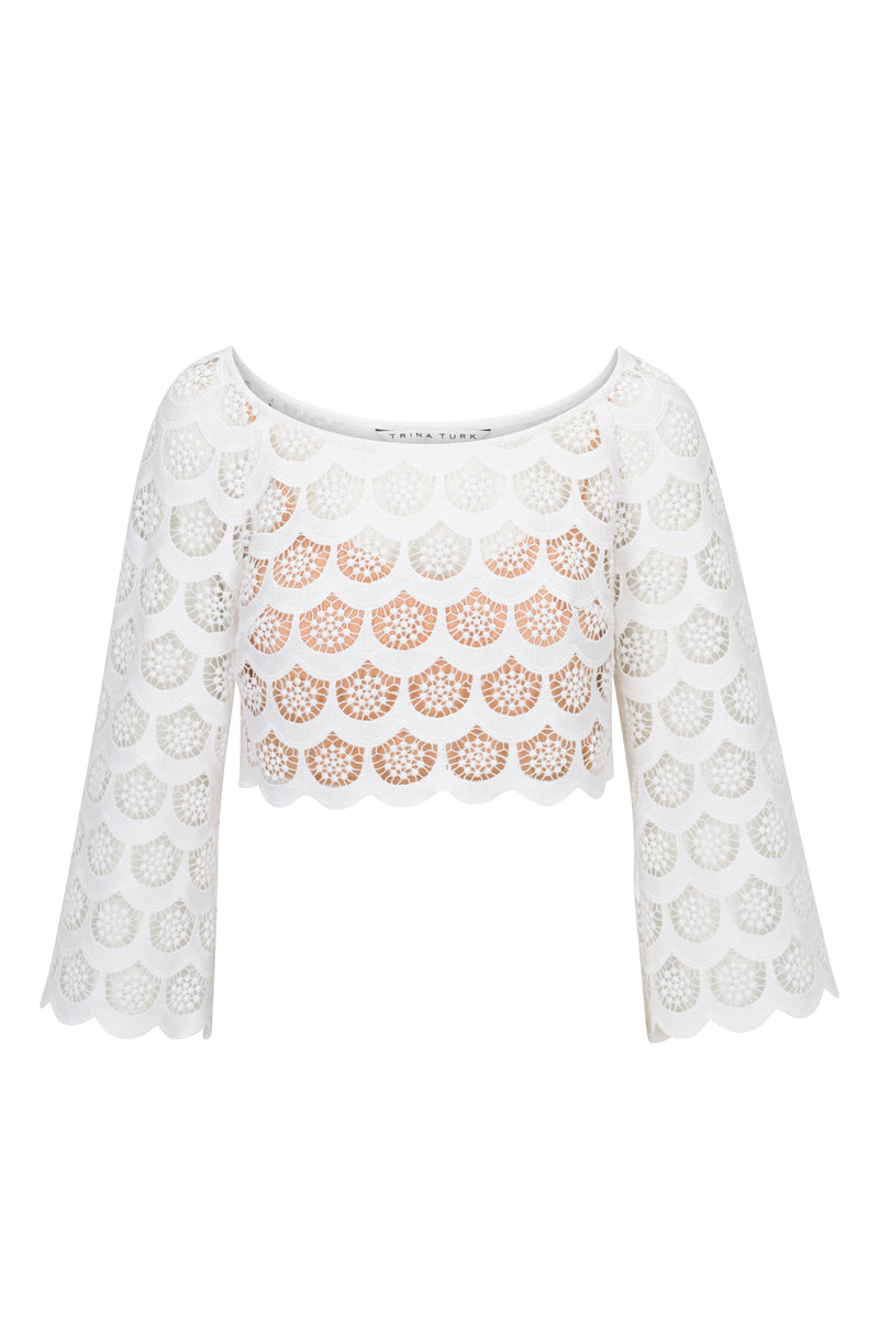 The Helen Crochet 3/4-Sleeve Crop Top features white, crocheted lace with a scalloped hem, circular cutouts over a light tan lining, and a wide boat neckline.