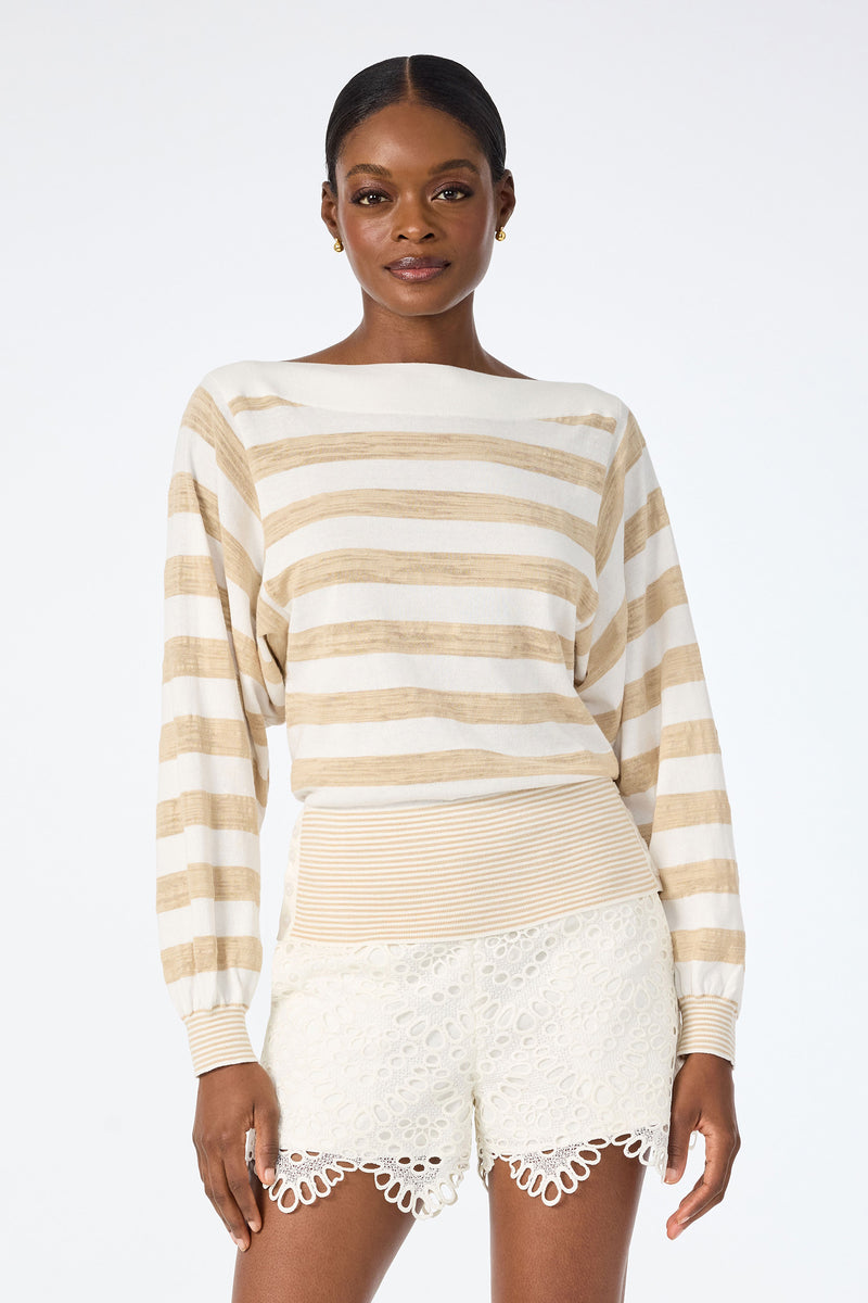 A woman wears the Ramona 2 Boatneck Sweater in Whitewash/Biarritz Beige with cream lace shorts, standing confidently against a plain white background.
