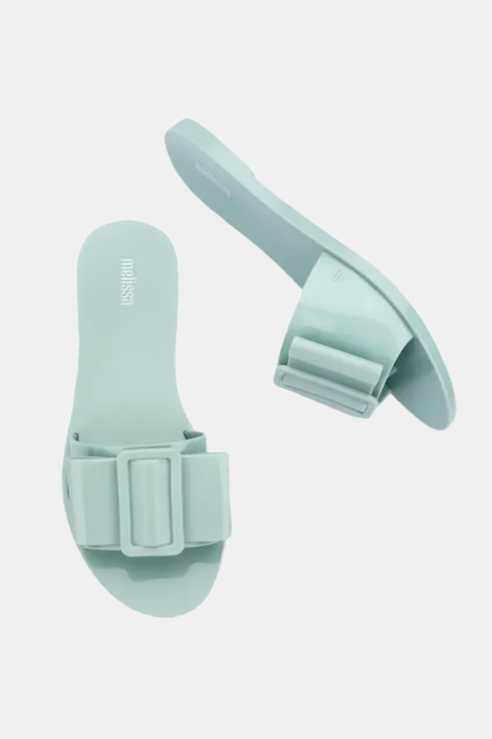 The Melissa Babe Sandal is a pair of light mint green slides featuring thick, decorative rectangular buckles on the straps, shown against a plain white background.