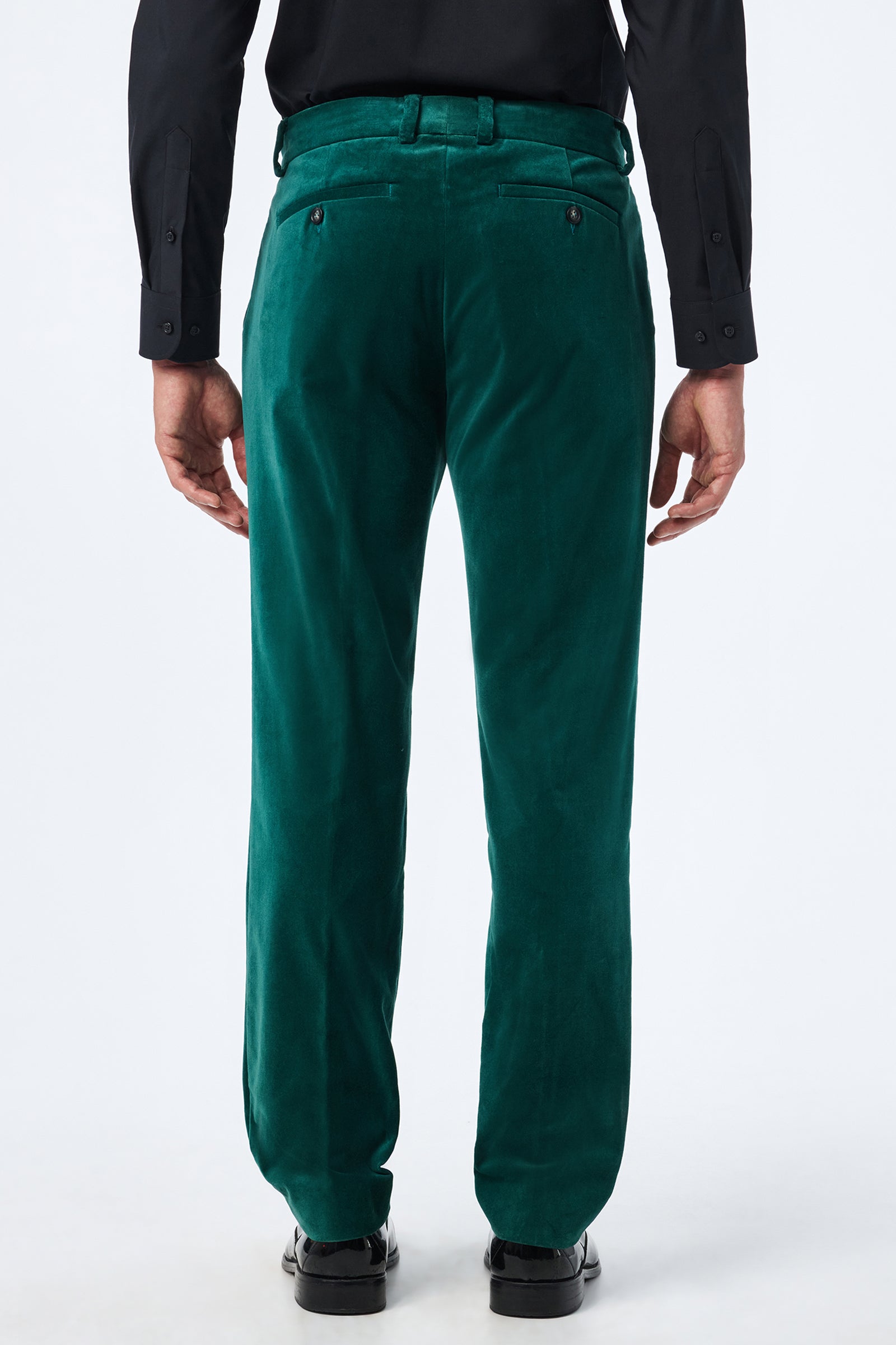 A man seen from behind wearing Clyde Slim Velvet Trouser in bright green, a black dress shirt, and black dress shoes, standing against a plain white background.