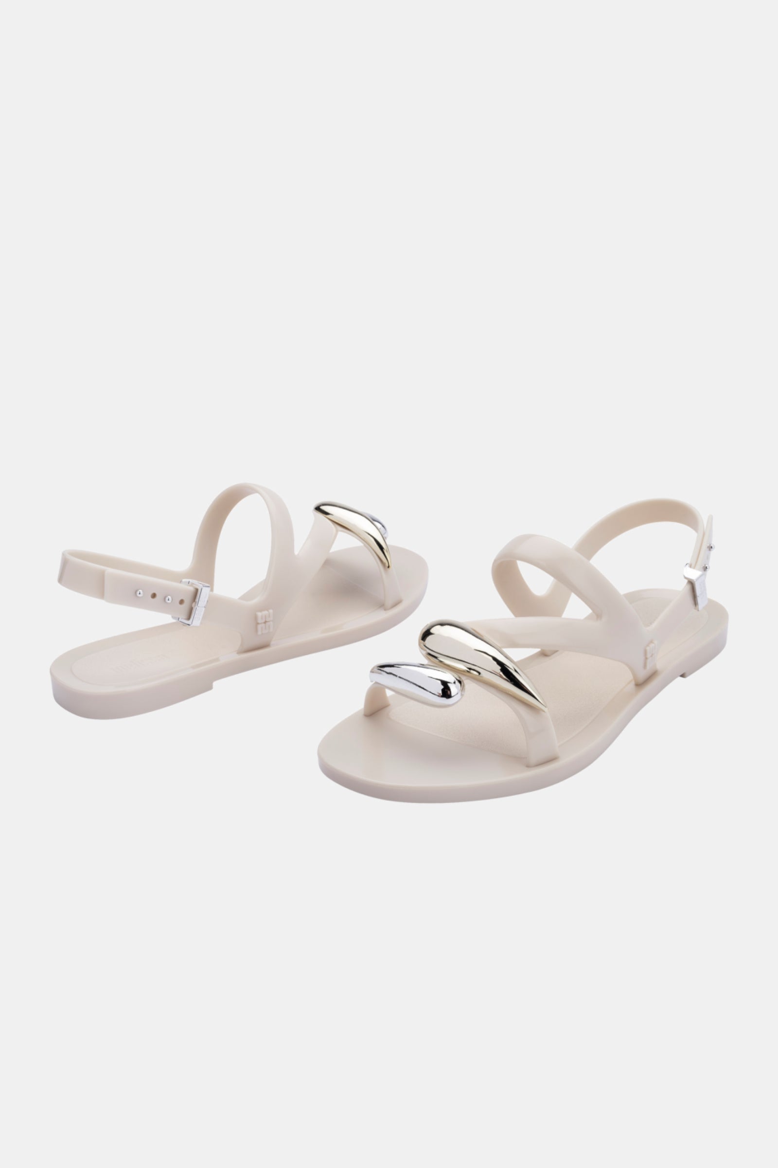 The Melissa Iris Sandal is a pair of white flats with ankle straps and metallic silver horn-shaped accents on the front, shown against a plain white background.