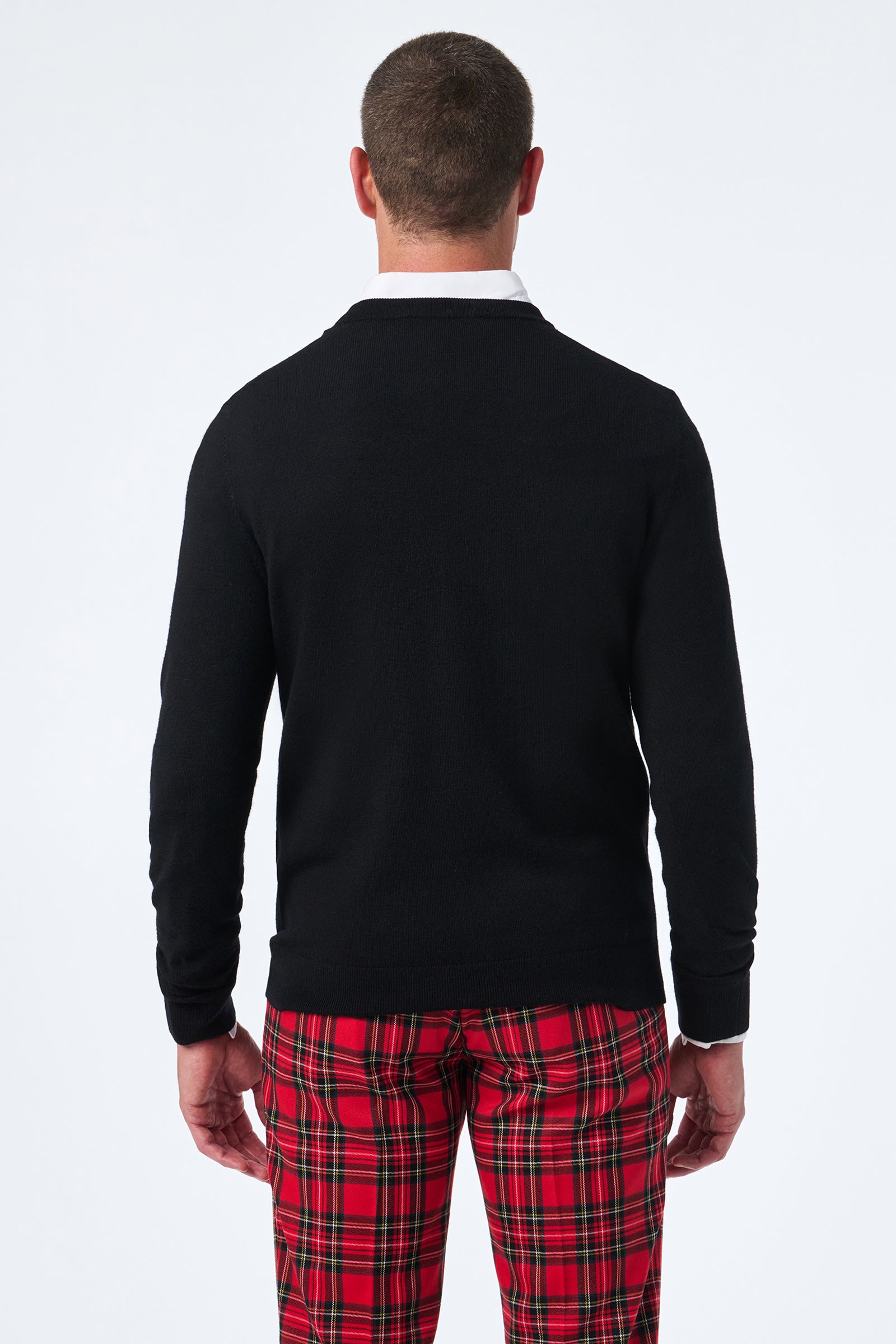 A man stands facing away, wearing the Martini Crewneck with a white collared shirt and red plaid pants against a plain white background.