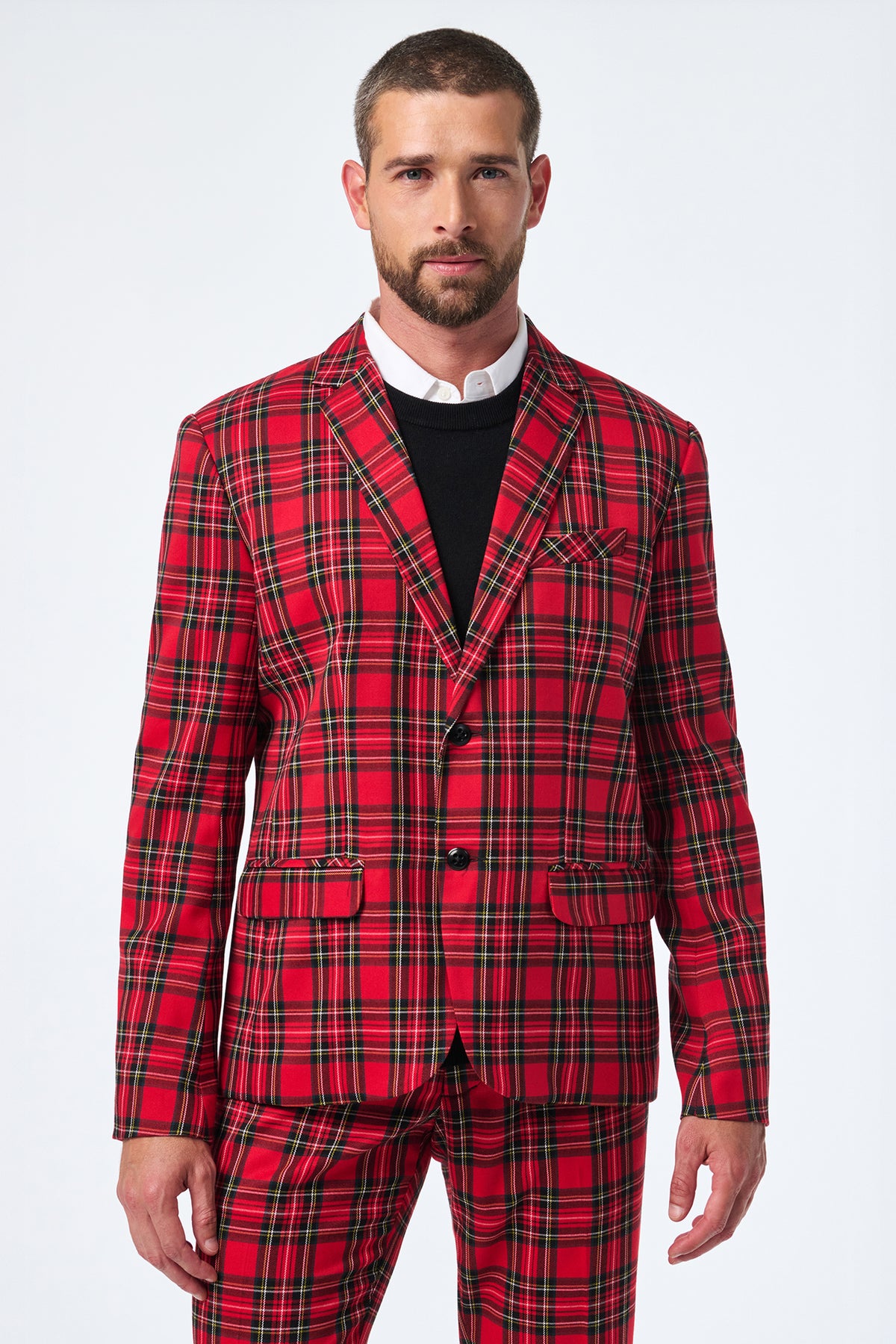 A man faces forward, wearing the Thurston Tartan Blazer in bright red plaid with black and yellow stripes over a white dress shirt and black sweater. The background is plain white.