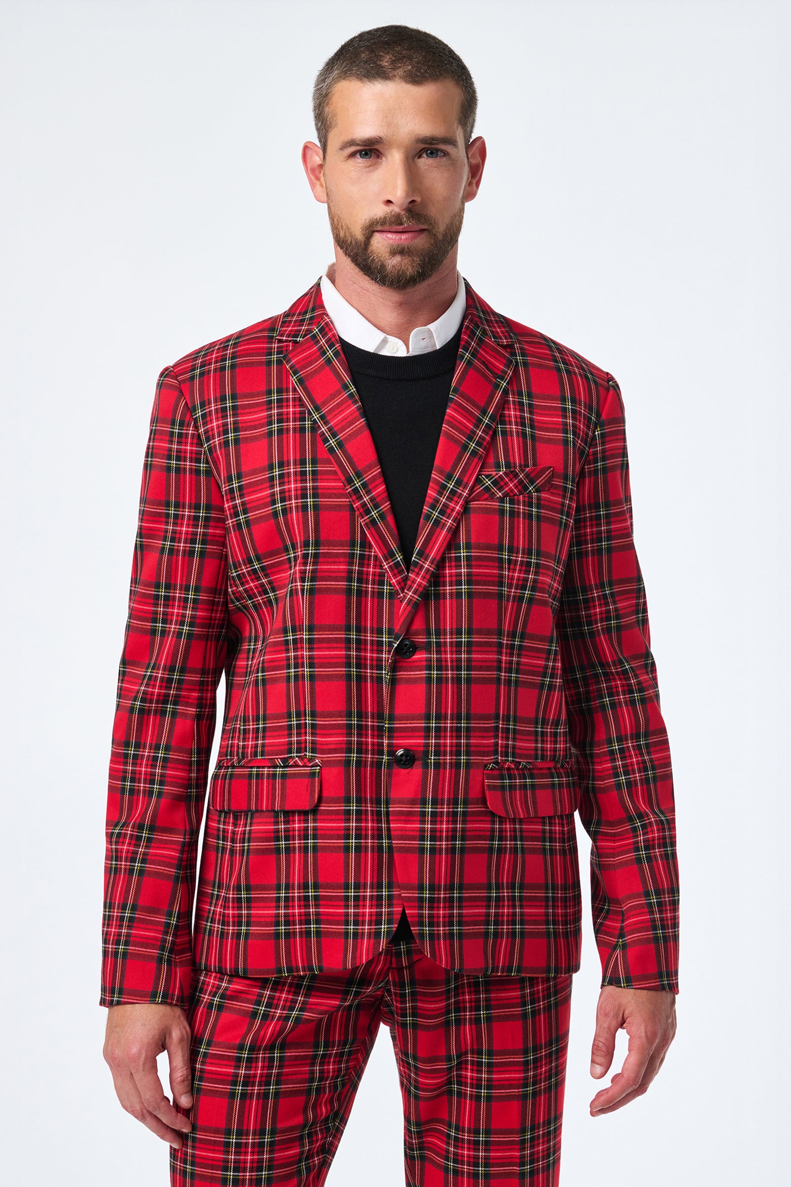 A man faces forward, wearing the Thurston Tartan Blazer in bright red plaid with black and yellow stripes over a white dress shirt and black sweater. The background is plain white.