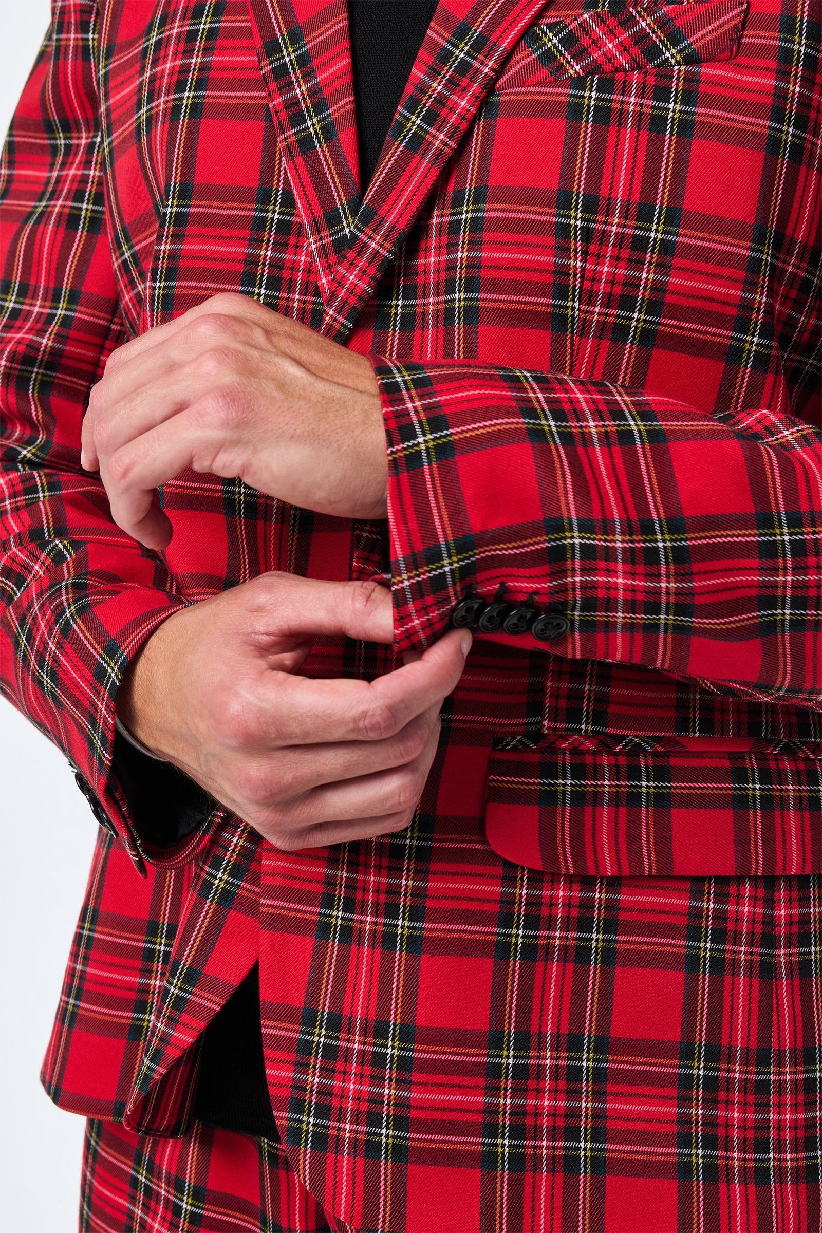 A person in the Thurston Tartan Blazer adjusts their jacket cuff while holding the sleeve. The blazer features a vibrant red, black, and yellow tartan plaid pattern.