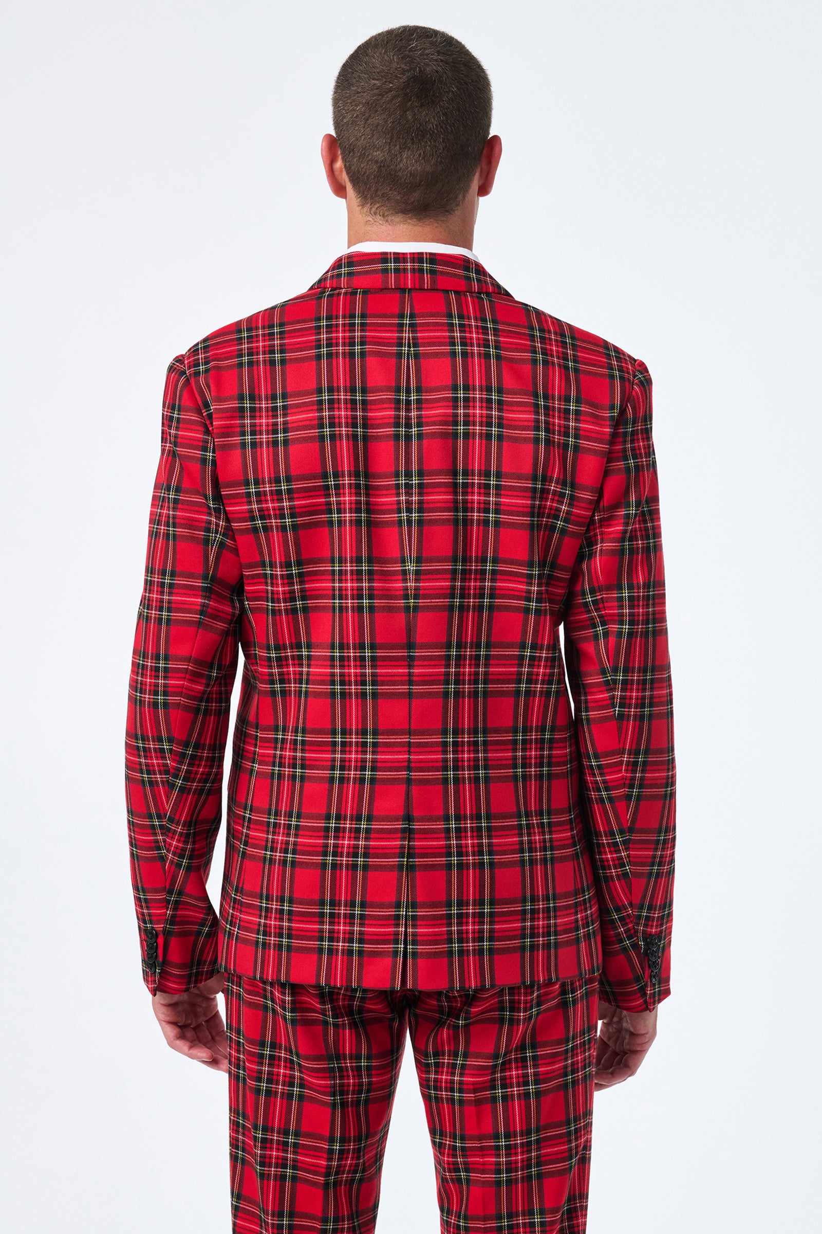 A person faces away, showing only the back and head while wearing the Thurston Tartan Blazer in red plaid with green and black stripes. The background is plain white.