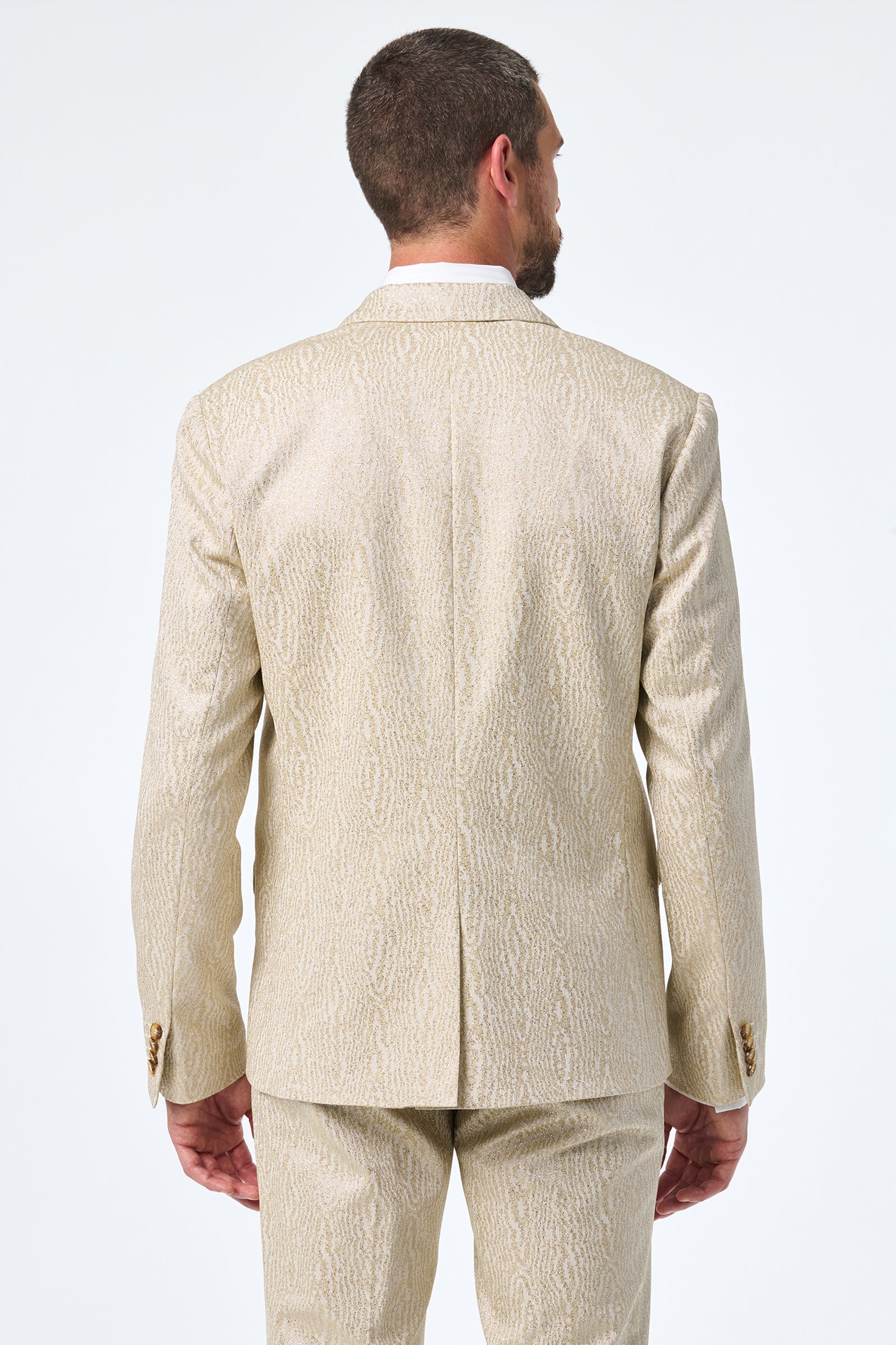 A man with short hair and a beard is seen from the back, wearing the cream-colored, textured Thurston Blazer with a subtle pattern against a plain white background.