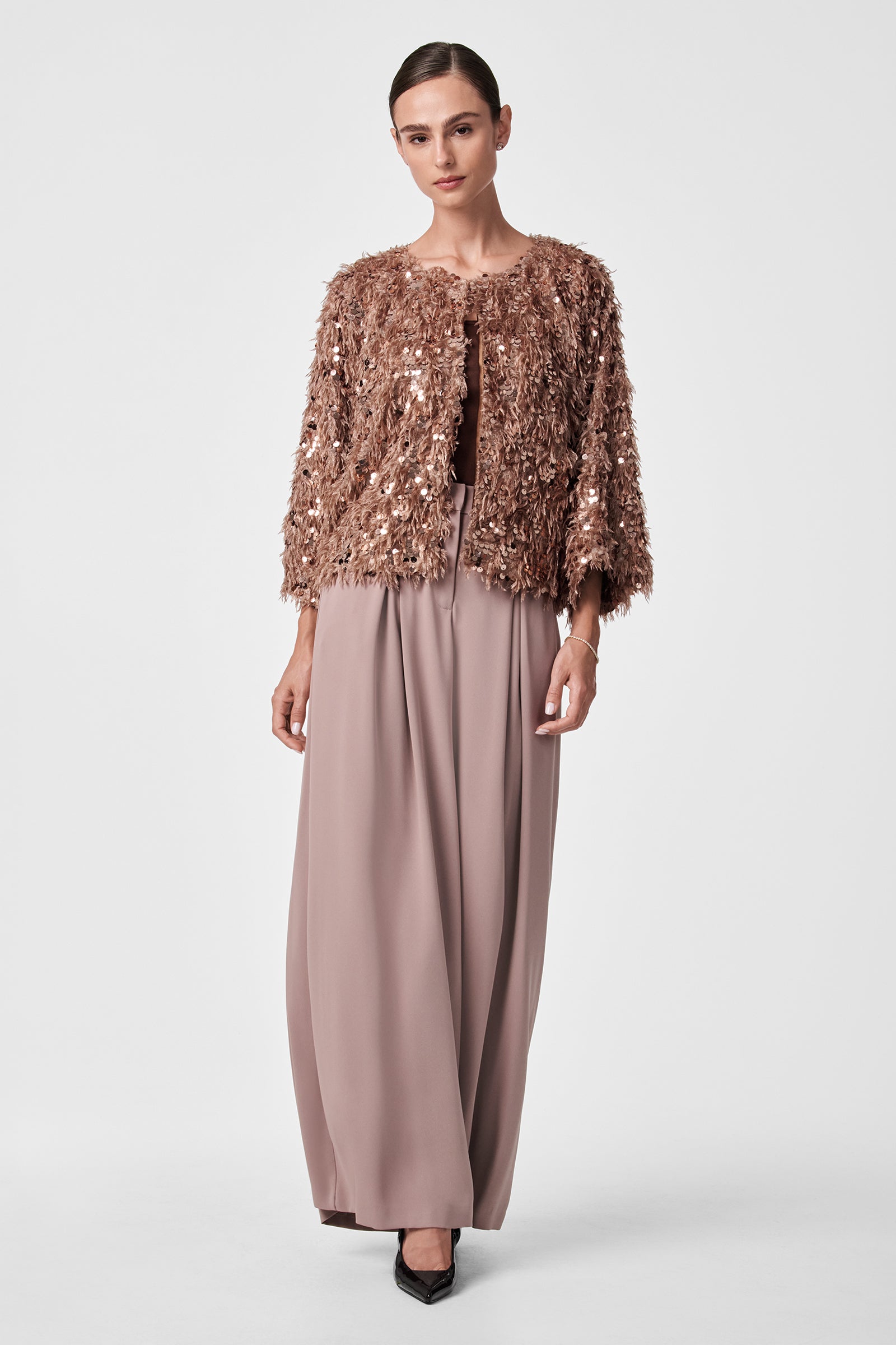 A woman stands against a plain background wearing the Fete Faux Fur Stole over a mauve floor-length skirt with black pointed heels. Her hair is pulled back and she has a neutral expression.
