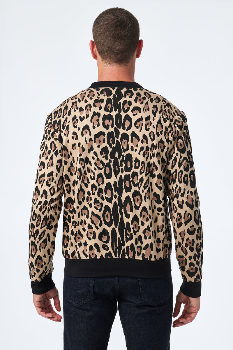 A man with short hair, seen from the back, wears the Darryl Knit Cardigan—a long-sleeve leopard print cardigan featuring black trim at the cuffs and hem—while standing against a plain white background.