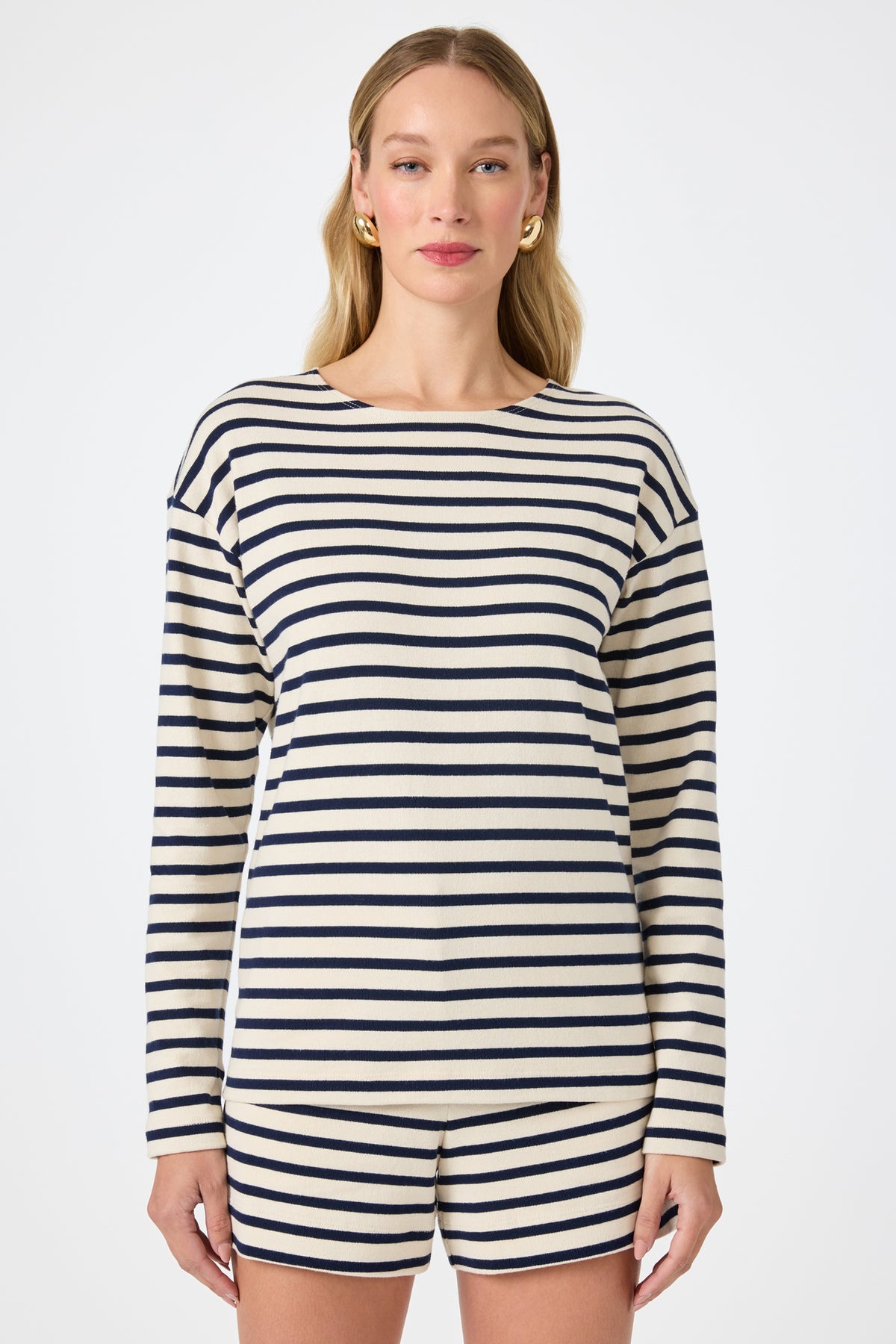 A woman with long blonde hair wears the Novena Top in Noh Nightfall Stripe. She faces forward against a plain white background.