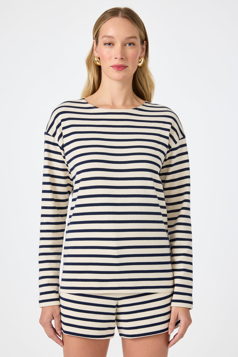 A woman with long blonde hair wears the Novena Top in Noh Nightfall Stripe. She faces forward against a plain white background.