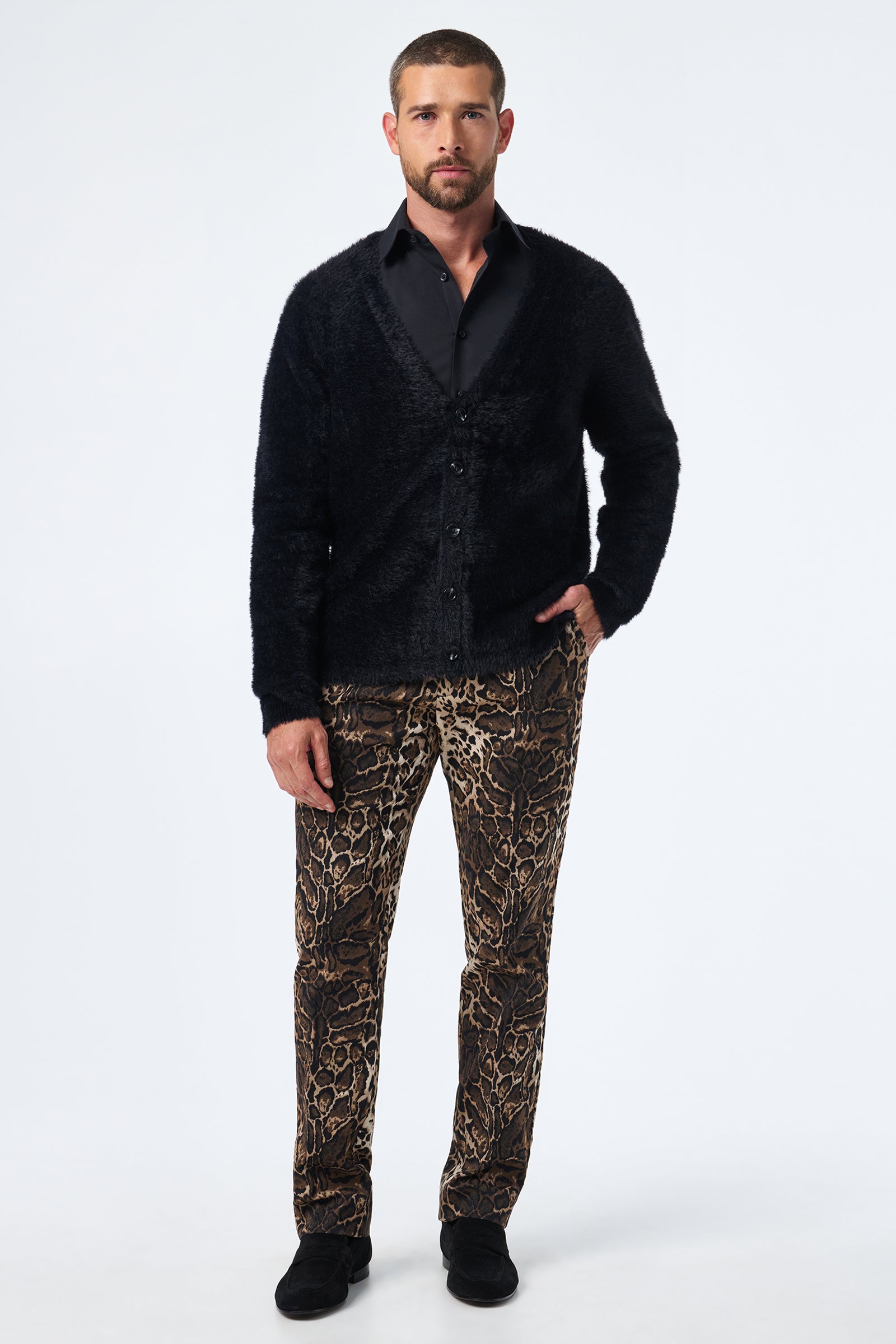 A man faces forward against a plain white background, wearing the Scott Fuzzy Cardigan in black, a black dress shirt, brown leopard-print pants, and black shoes.