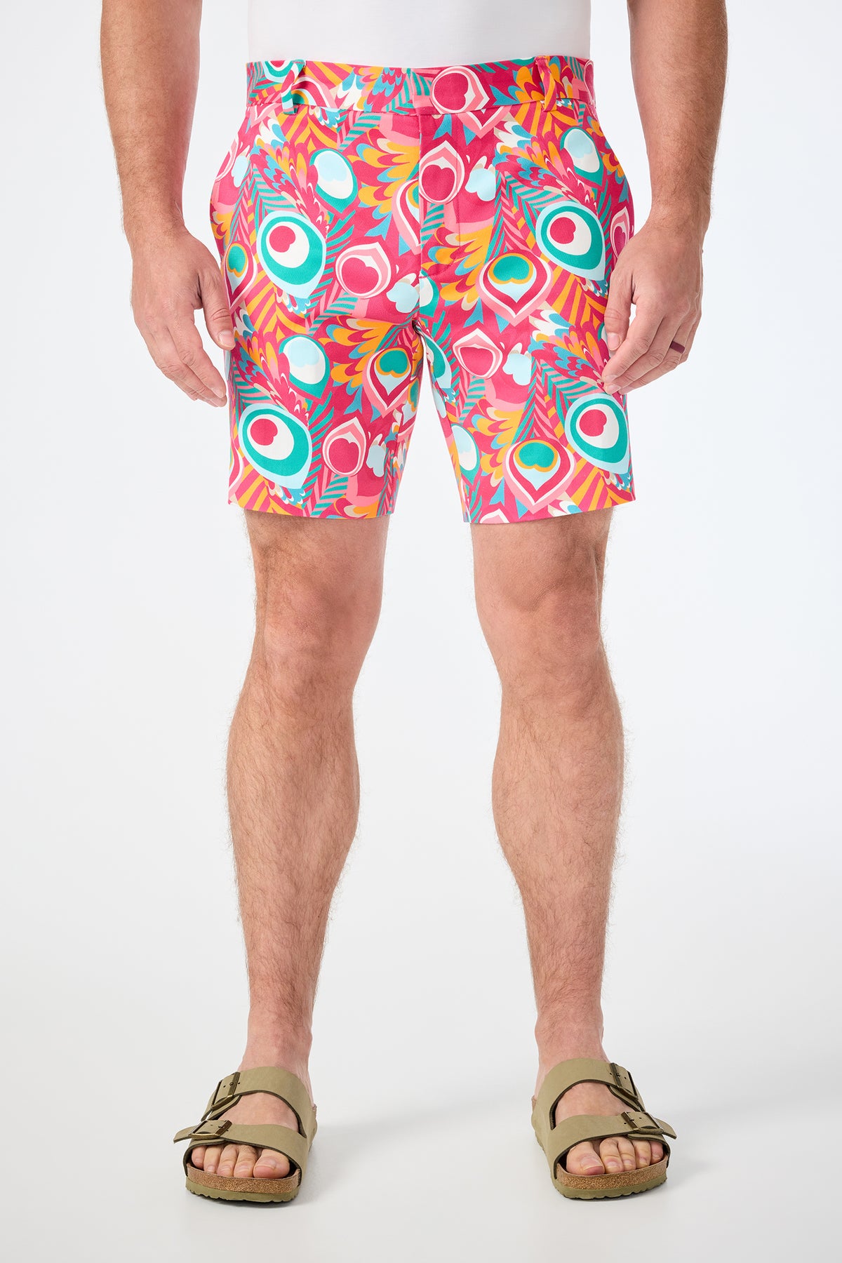 A person wearing the Lawrence Short in Dramont, featuring colorful abstract patterns, paired with tan sandals and standing against a plain white background.