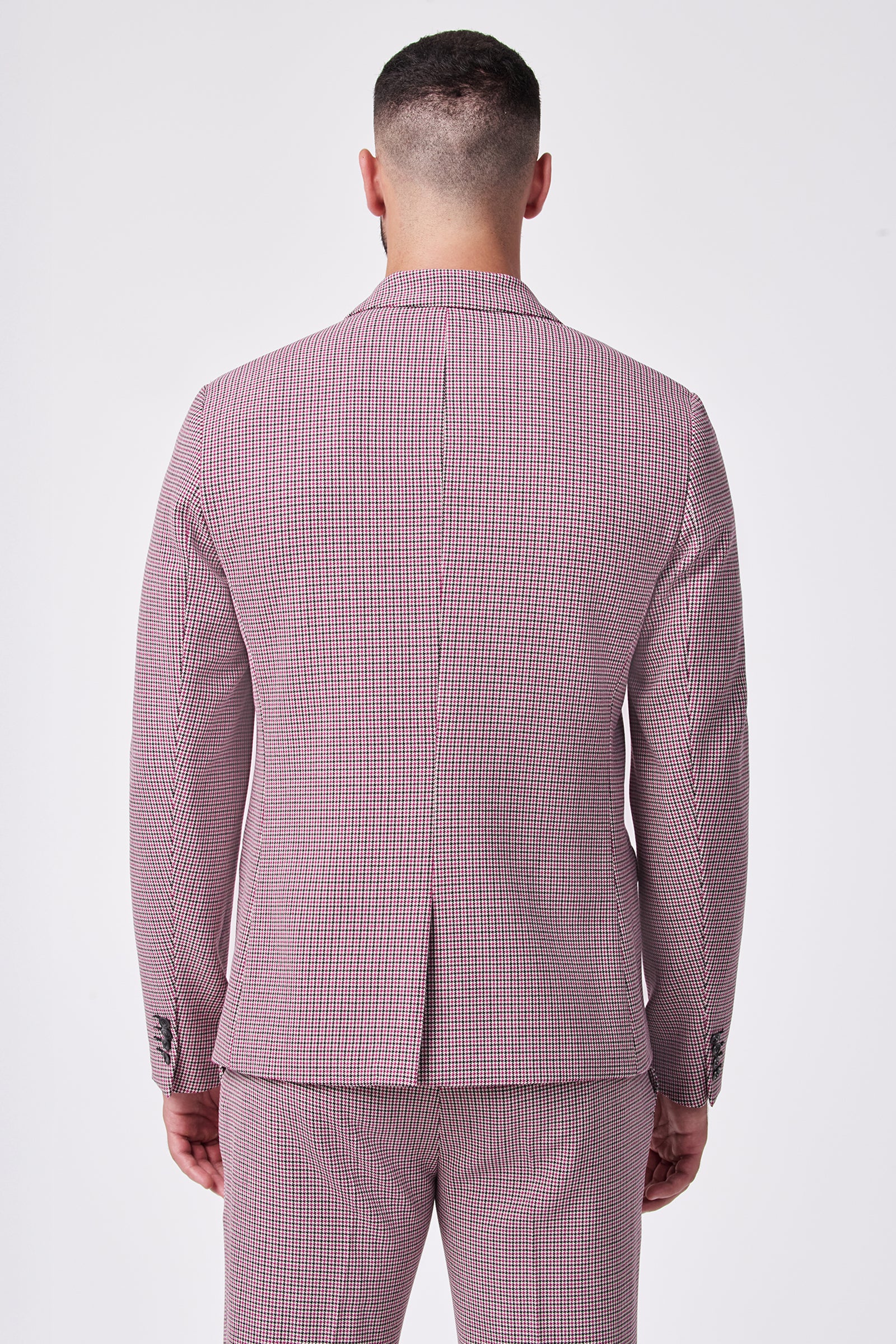 A man faces away from the camera in a fitted THURSTON BLAZER, a pink and white checkered suit made from a soft viscose blend with added elastane stretch, set against a plain white background.