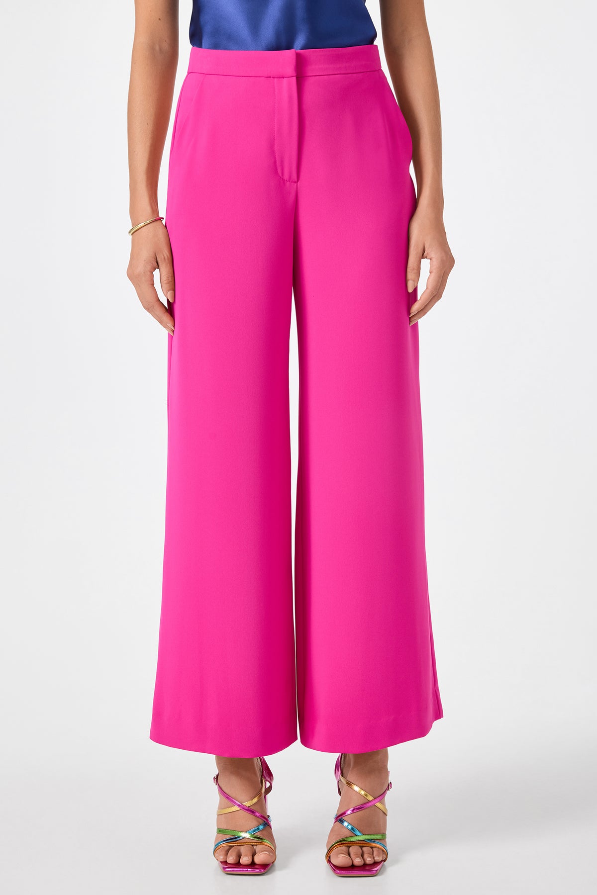 Someone wears Verity 3 Wide-Leg Pants in Trina Pink, paired with a blue top and strappy high-heeled sandals, standing against a plain white background.