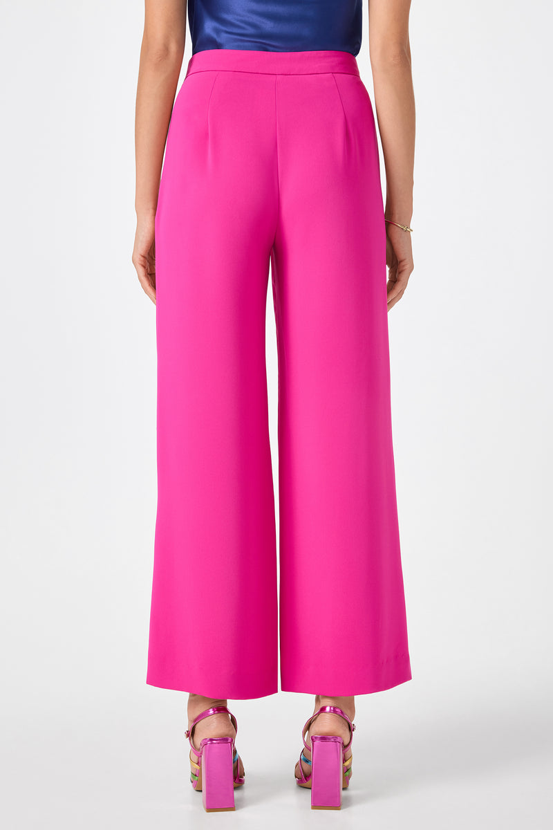 A person poses from the back against a plain white background, wearing Verity 3 Wide-Leg Pants in bright pink with colorful high-heeled sandals.
