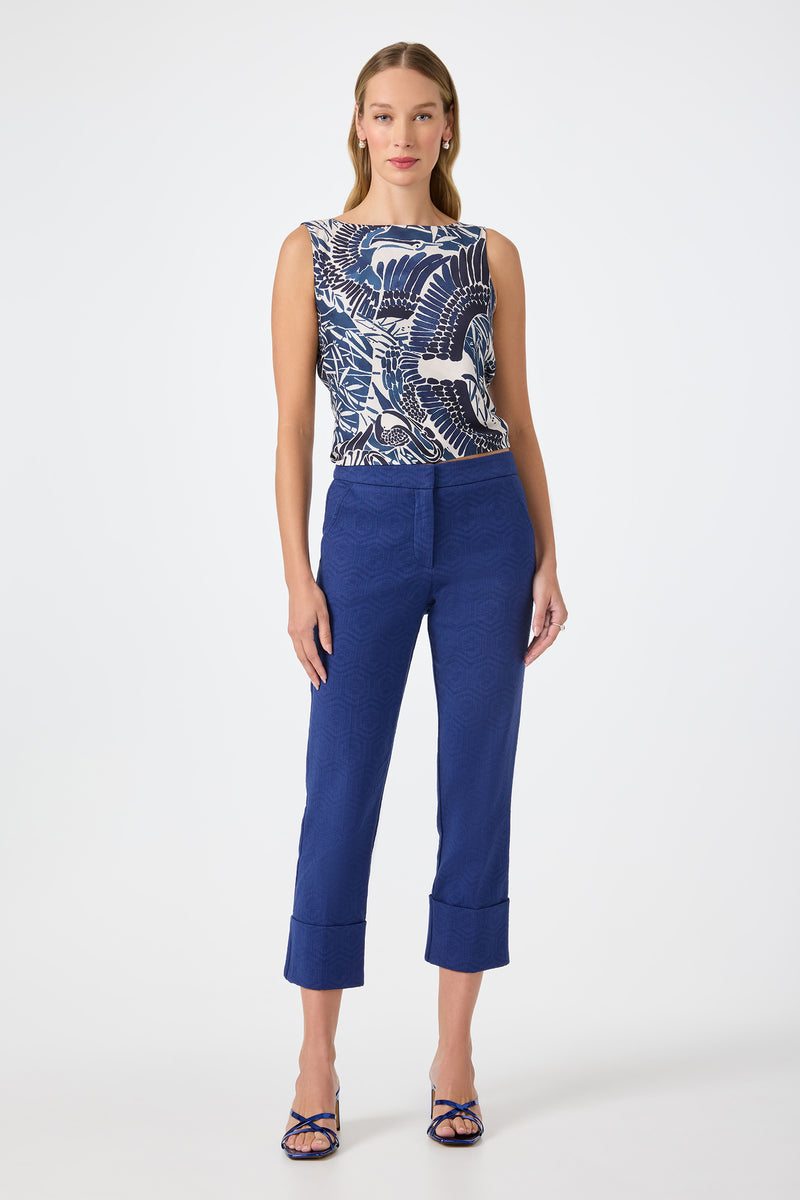 A woman faces forward against a white background, wearing a sleeveless top with a bold blue and white wave pattern, blue strappy heels, and Banshee Cropped Cuff Hem Pants.