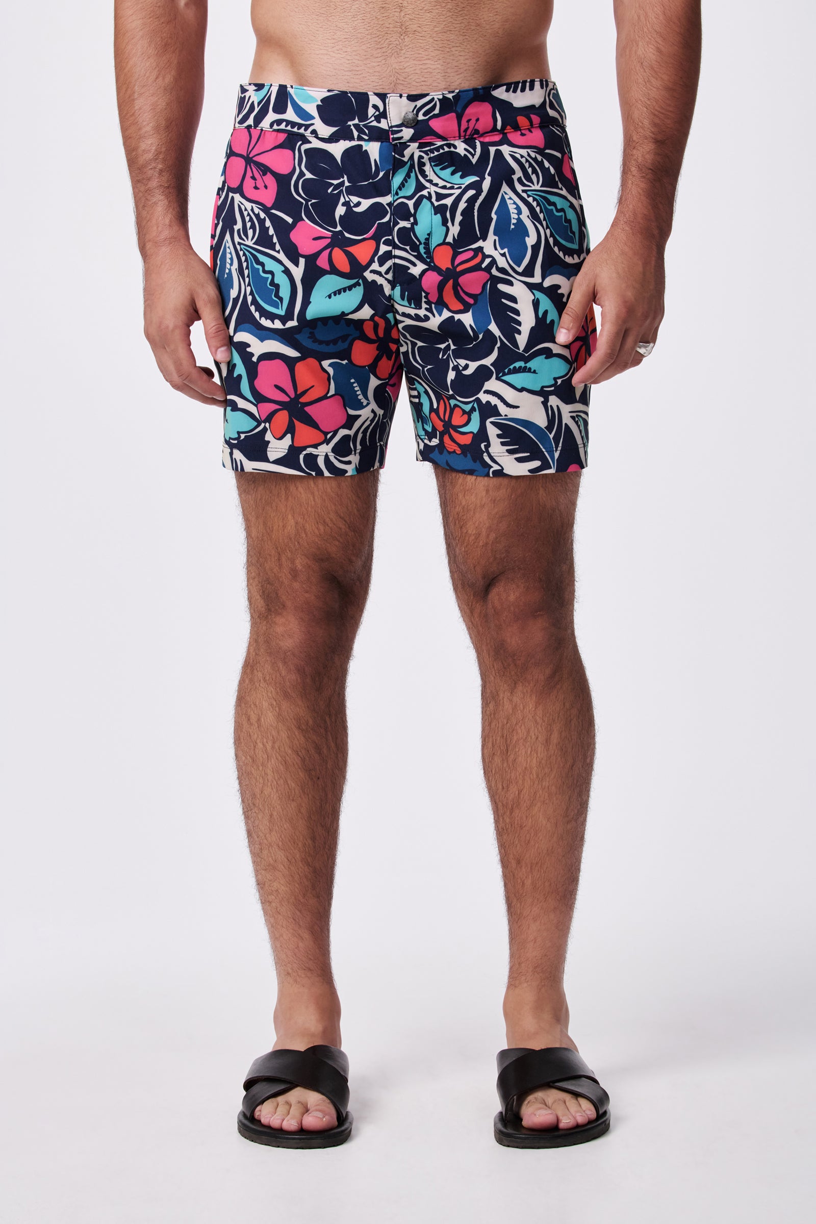 A person is shown from the shoulders down wearing the Honolulu Board Short - Copacabana and black slide sandals against a plain white background.