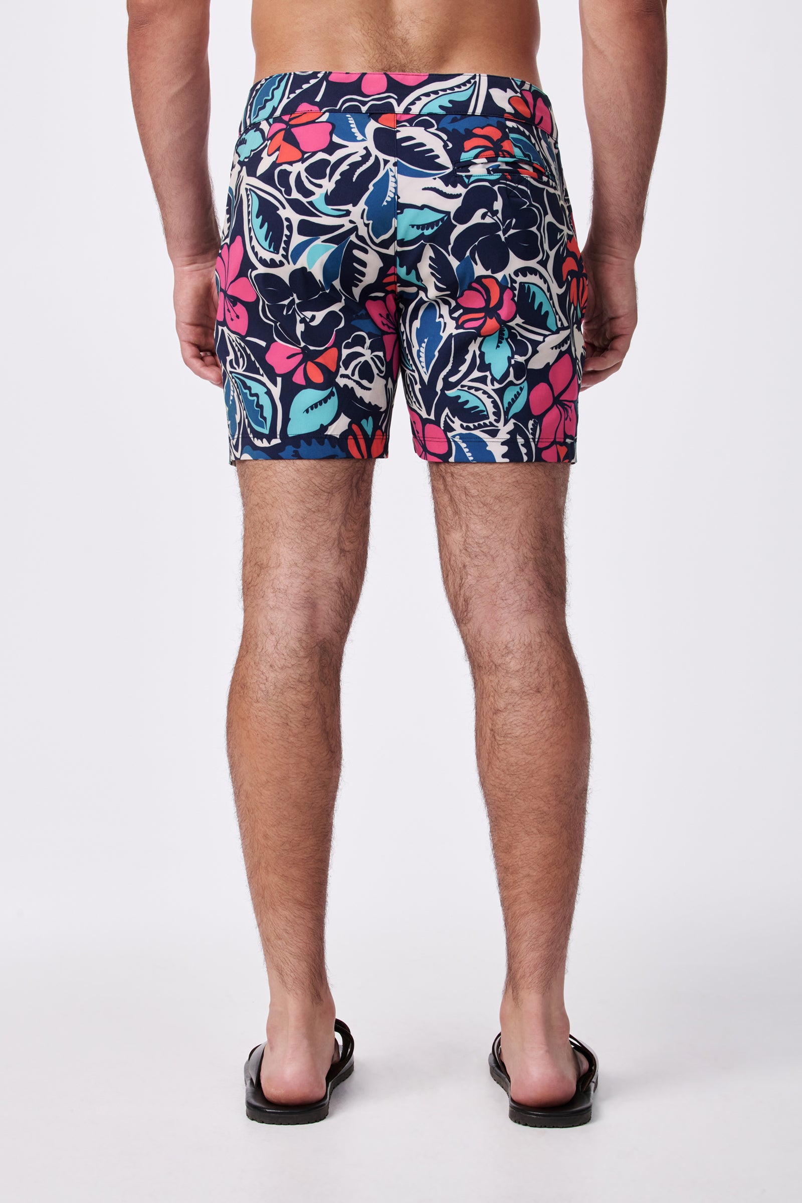 A man stands facing away against a plain white background, wearing the Honolulu Board Short - Copacabana and black flip-flops. His arms are relaxed by his sides.