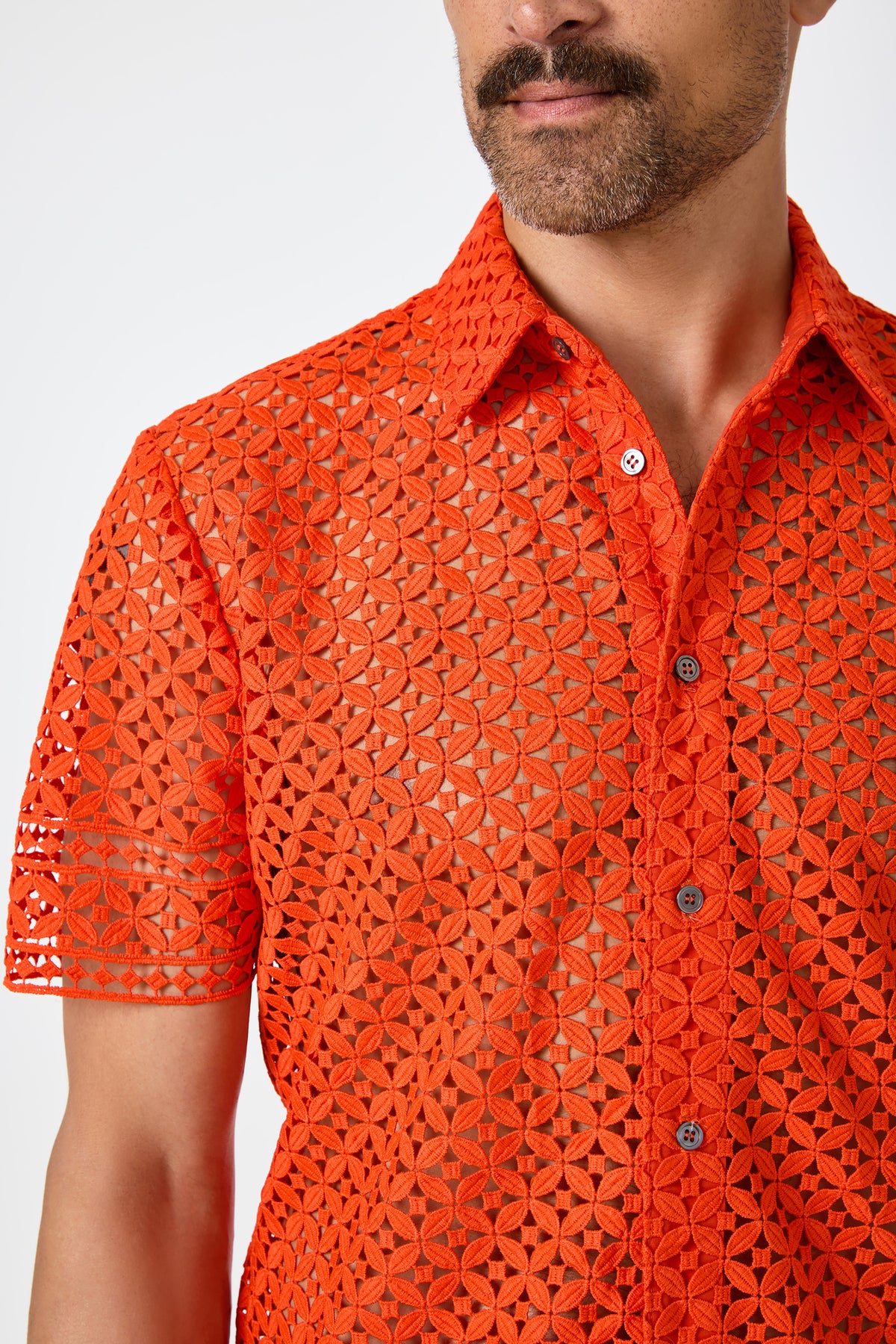 A man with a mustache wears the Belmont Shore Shirt‚Äö√Ñ√Æa bright orange, short-sleeved, button-up featuring a geometric see-through lace pattern. The image is cropped at his upper chest and mouth.